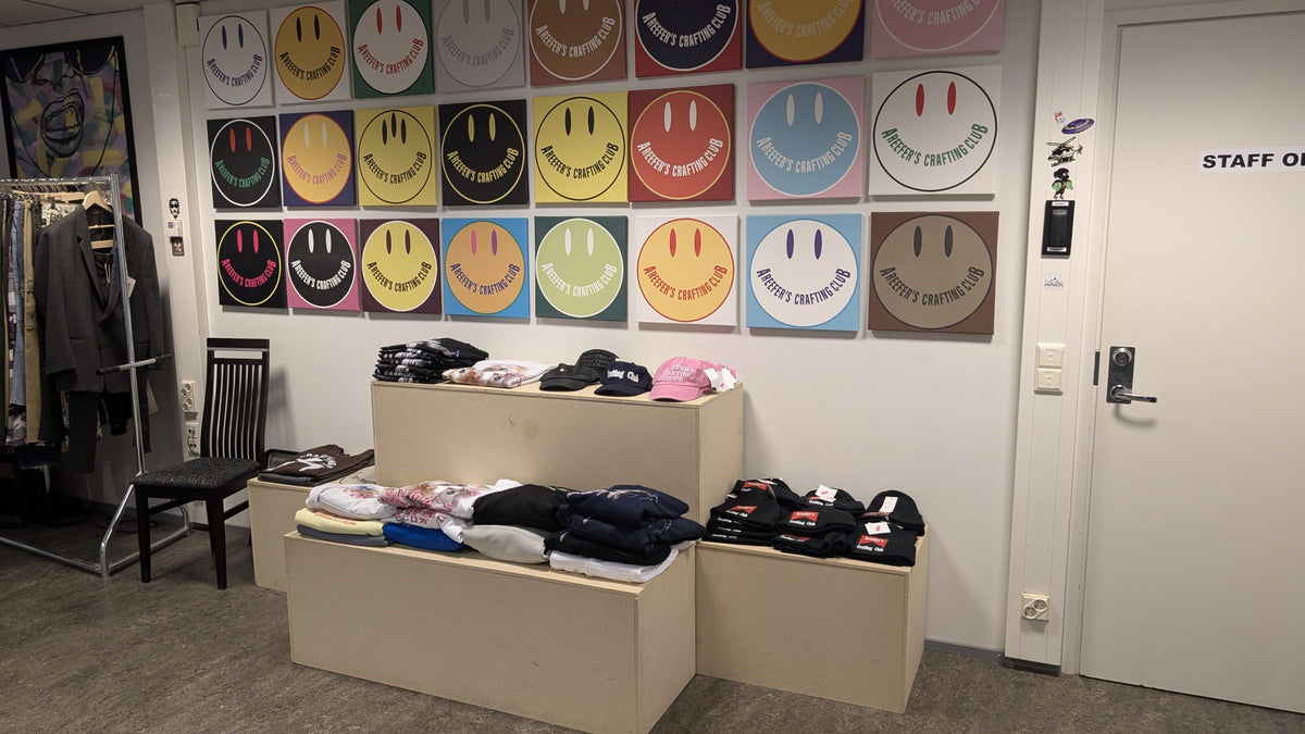 JAKE & IPI shop in Vallila: smiley logo art wall by Areefer’s Crafting Club above a table of folded clothes
