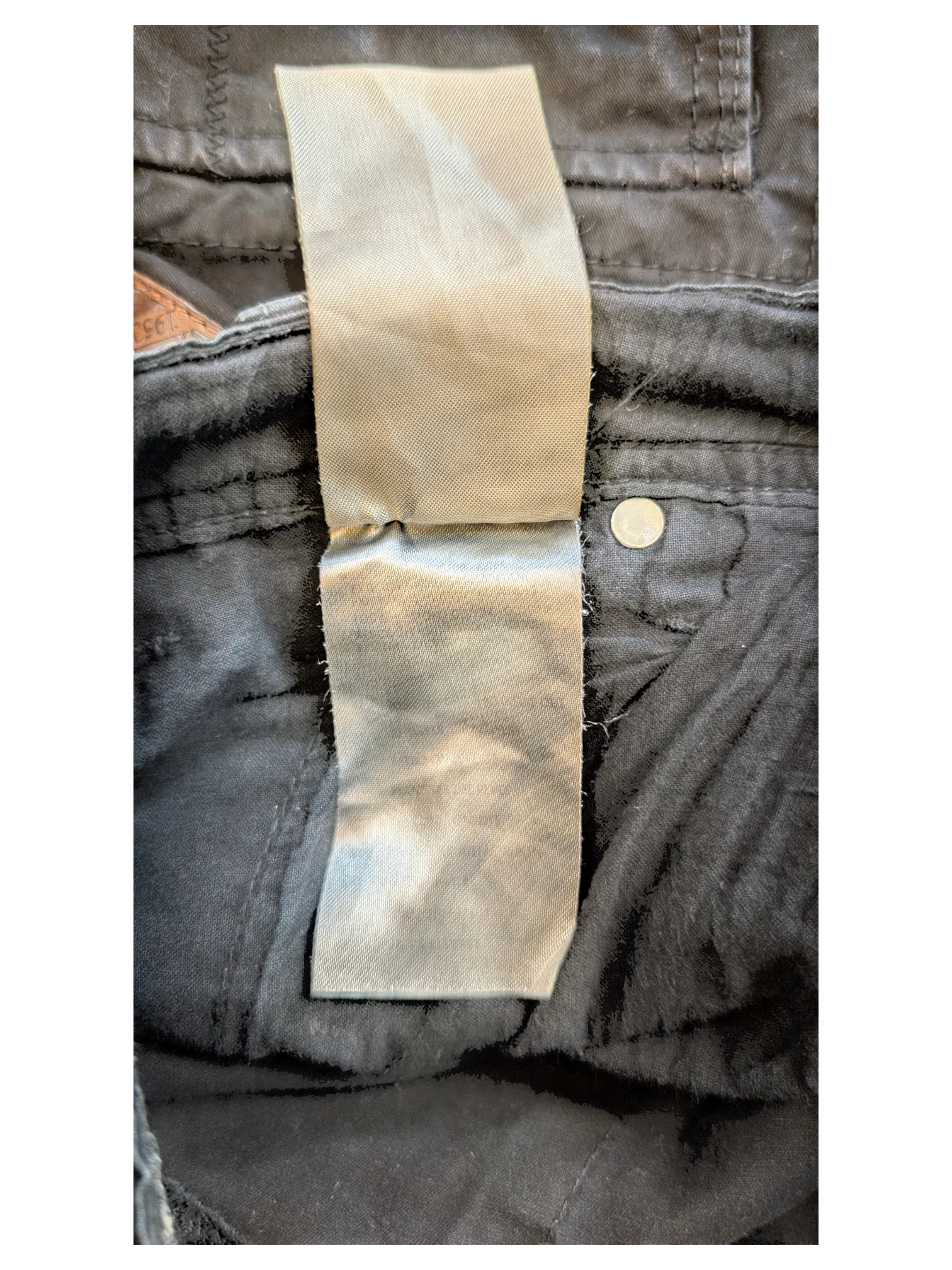 JAKE & IPI black cargo pants with multiple pockets and a button closure. Close-up of the care label.