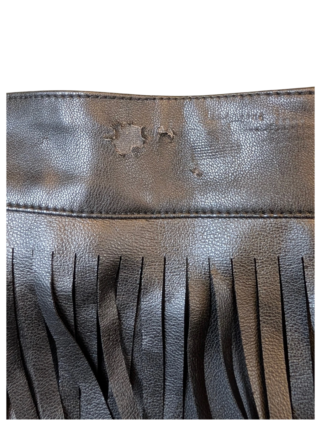 Close-up of JAKE & IPI black faux leather fringed mini skirt showing textured material and decorative fringe detail.