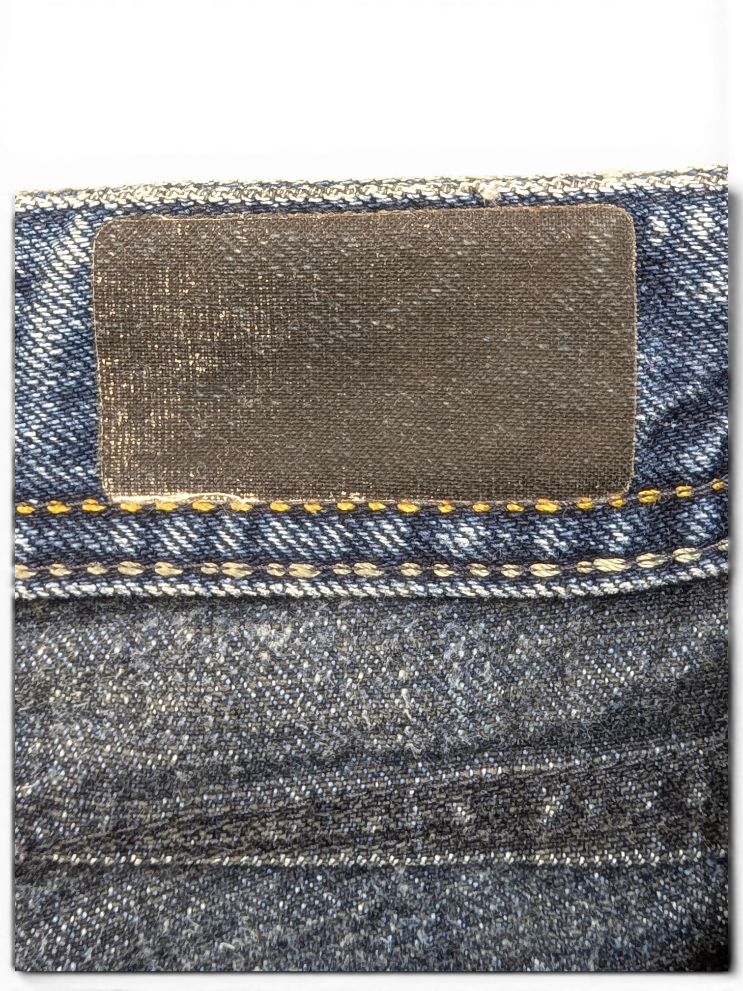 JAKE & IPI dark wash denim jeans with a black leather patch and yellow stitching detail.