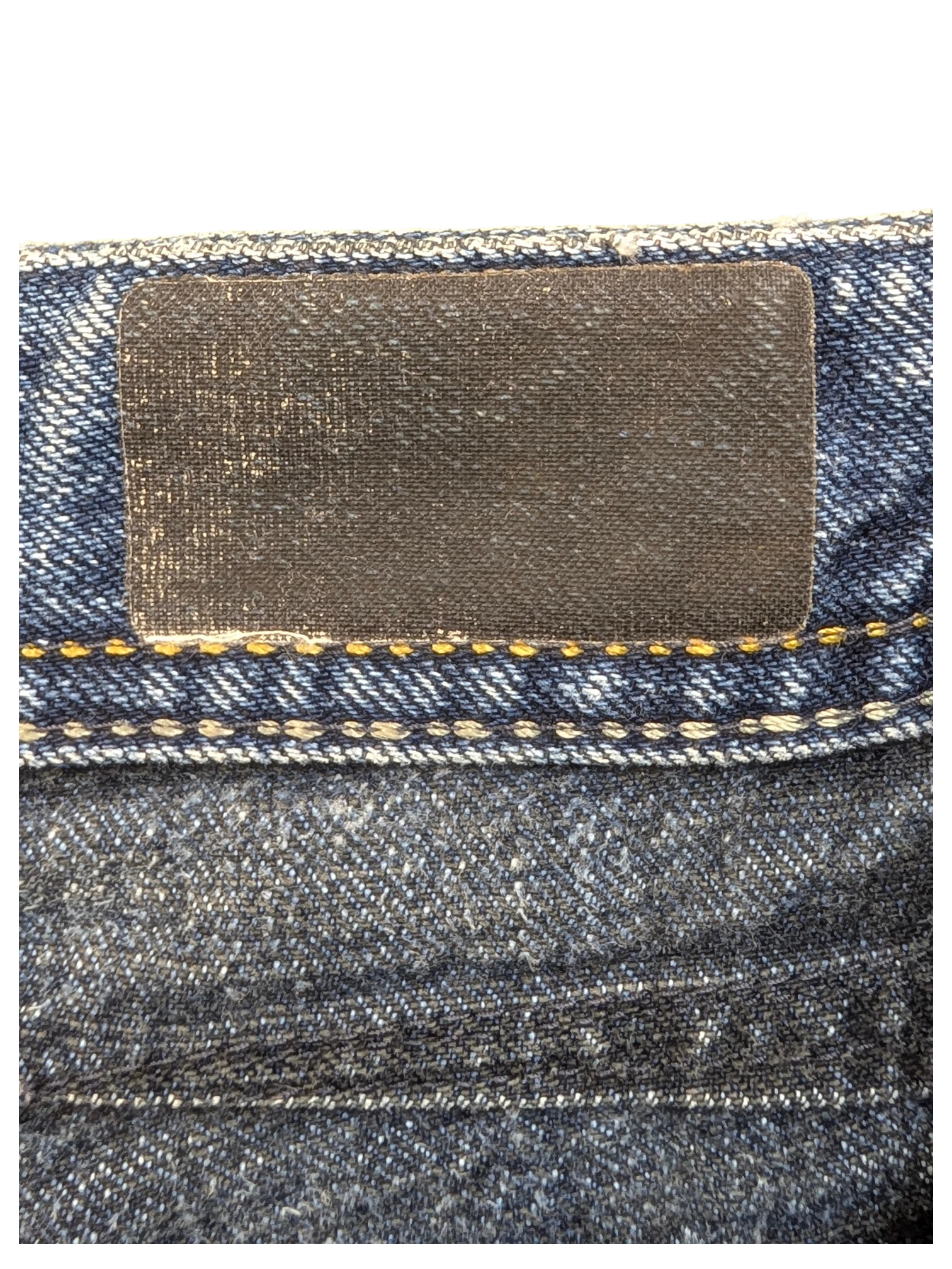 JAKE & IPI dark wash denim jeans with a black leather patch and yellow stitching detail.