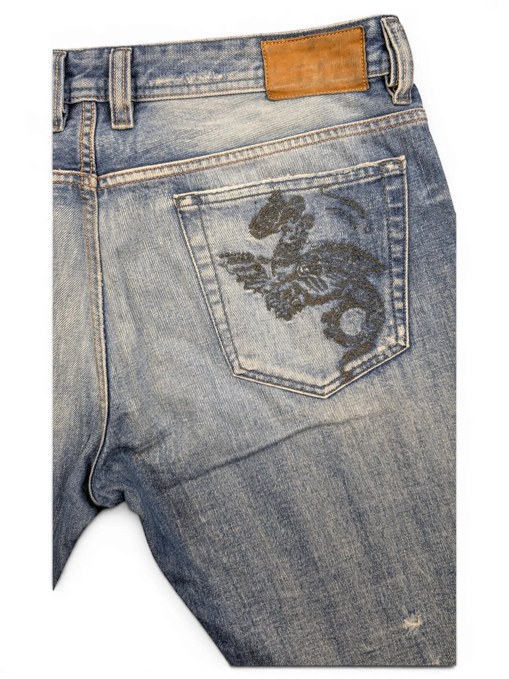 JAKE & IPI light wash denim jeans with a black dragon embroidered on the back pocket and a brown leather patch.