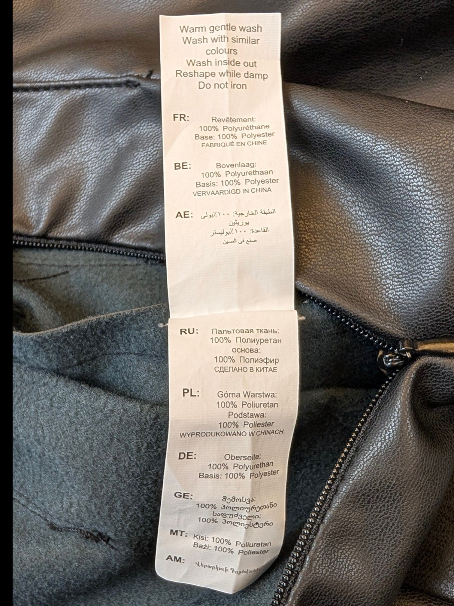 JAKE & IPI black faux leather pleated mini skirt care label showing 100% polyurethane and polyester composition