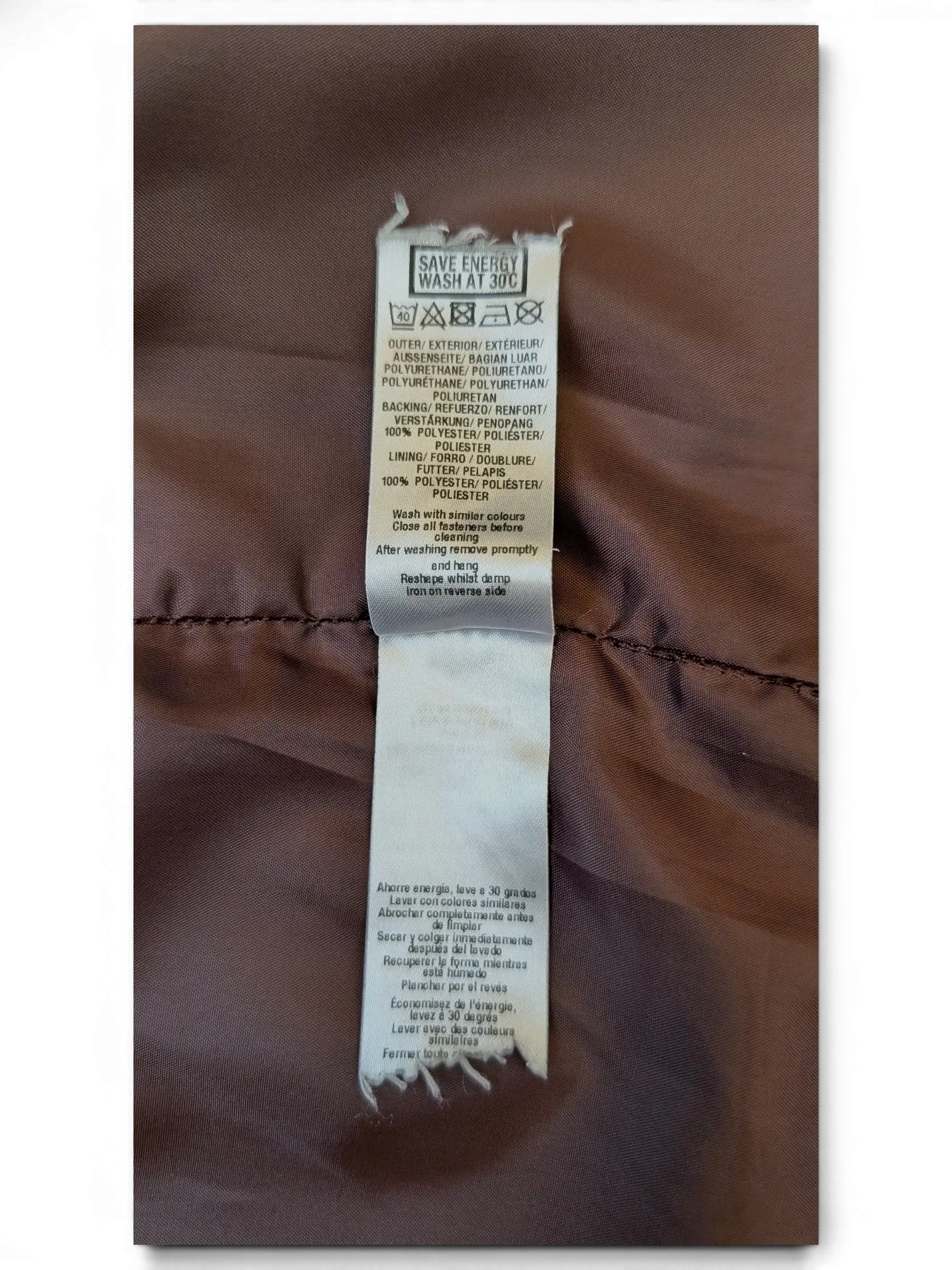 JAKE & IPI faux leather mini skirt care label showing polyurethane material and polyester lining details.