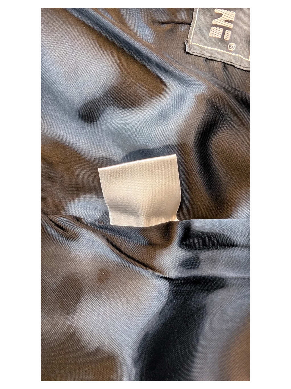 Interior lining and brand label of a JAKE & IPI Giorgio Mobiani leather skirt featuring black satin fabric.