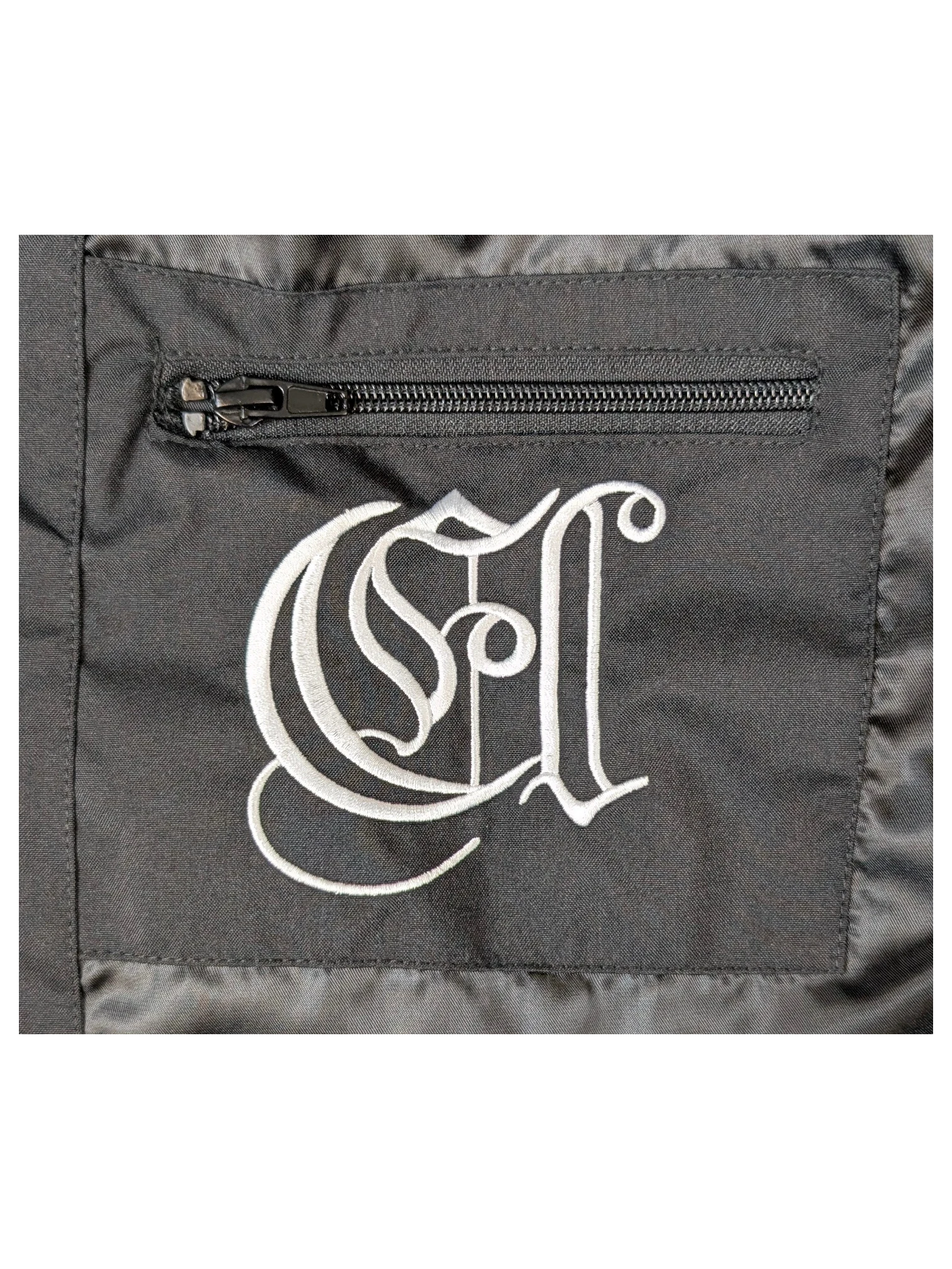 JAKE & IPI IBE Elenyor jacket black fabric with white embroidered gothic logo and zippered pocket detail