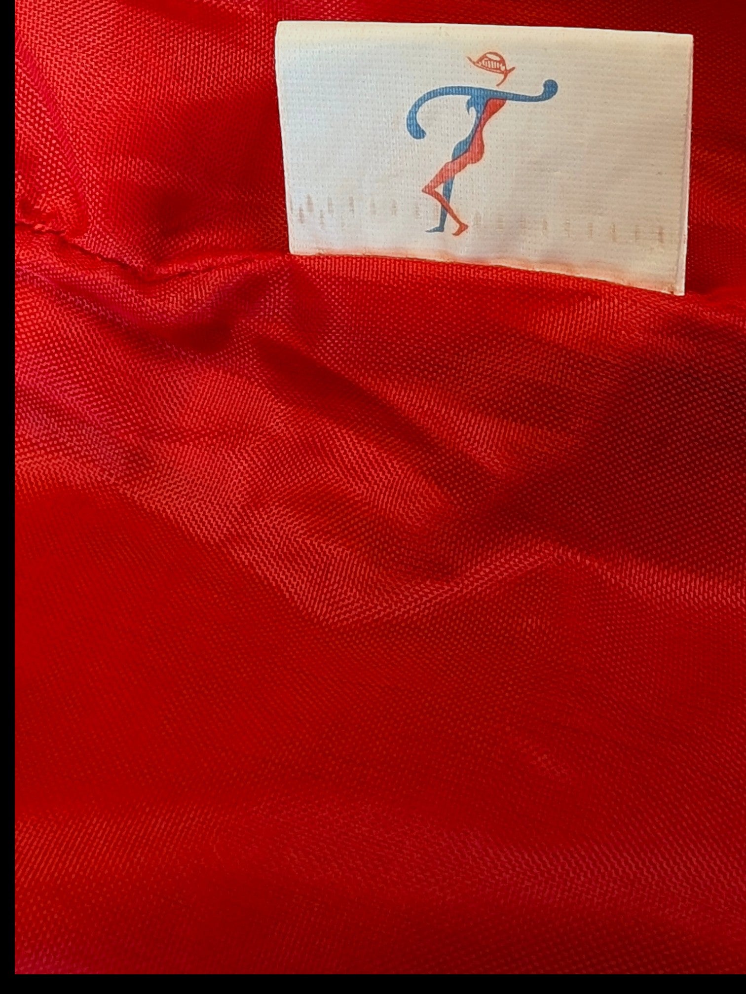 Interior red lining of a JAKE & IPI leather skirt featuring a white brand label with a stylized logo.