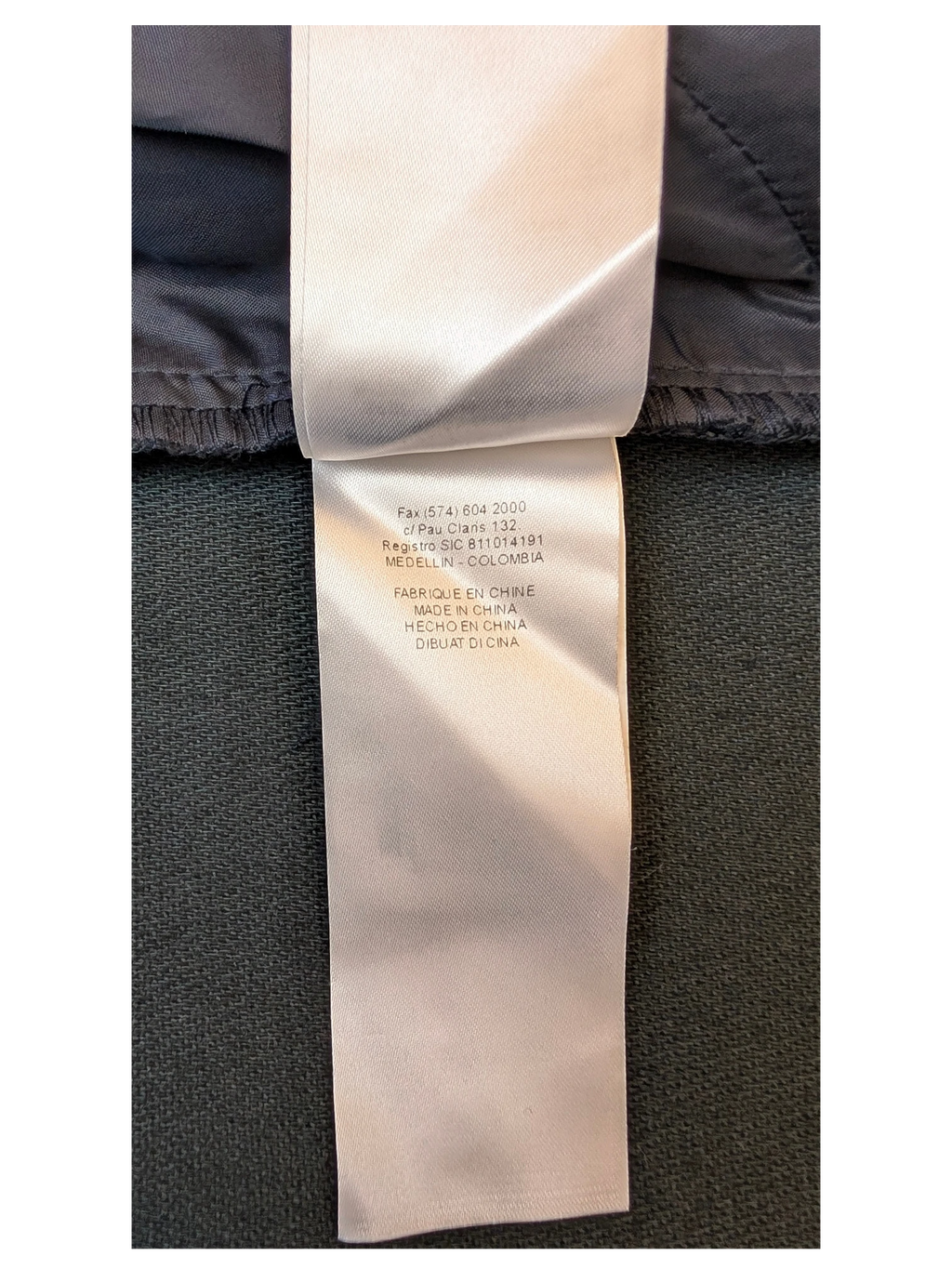 JAKE & IPI NAF NAF faux leather mini skirt care label with manufacturing details in white on dark fabric.