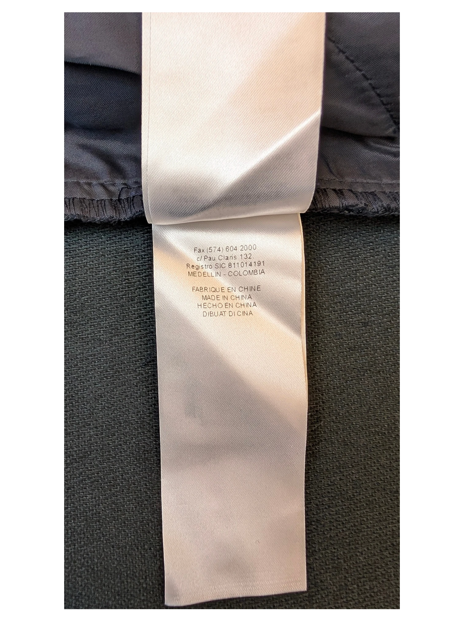 JAKE & IPI NAF NAF faux leather mini skirt care label with manufacturing details in white on dark fabric.