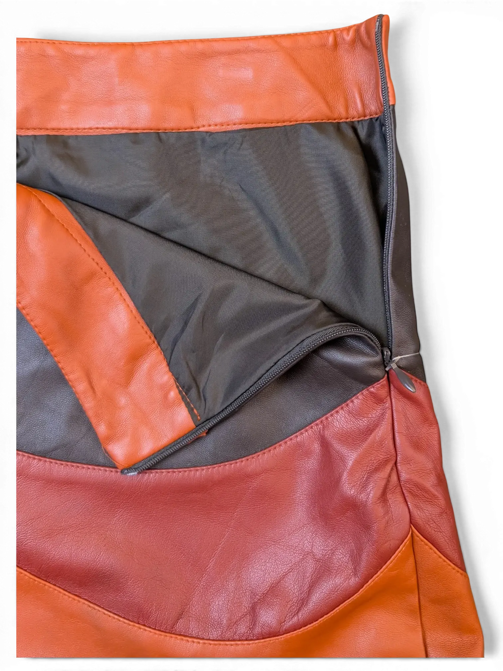 JAKE & IPI paneled faux leather mini skirt in orange, brown, and red with a side zipper and dark lining.