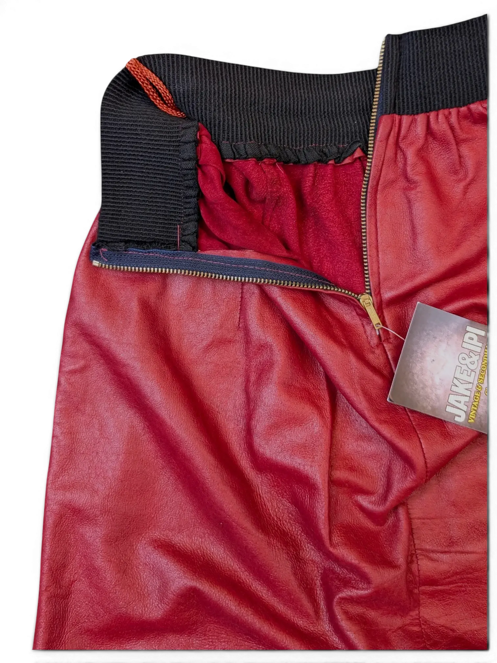 JAKE & IPI red faux leather skirt featuring a black ribbed elastic waistband and a front metal zipper closure.