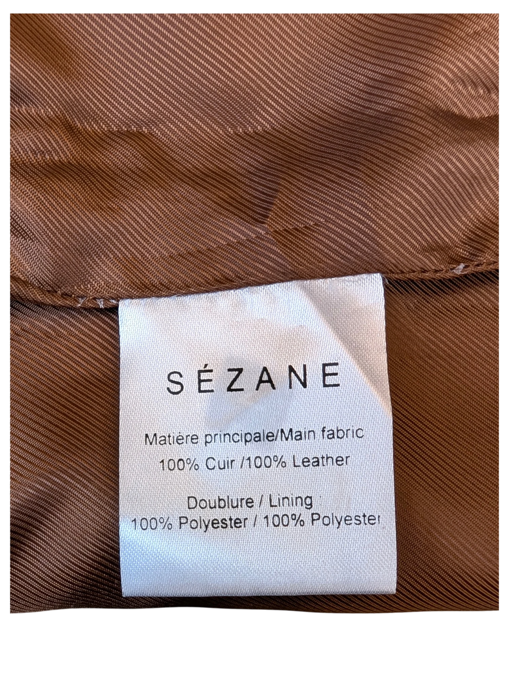 JAKE & IPI Sézane leather skirt care label showing 100% leather and 100% polyester lining on brown fabric.