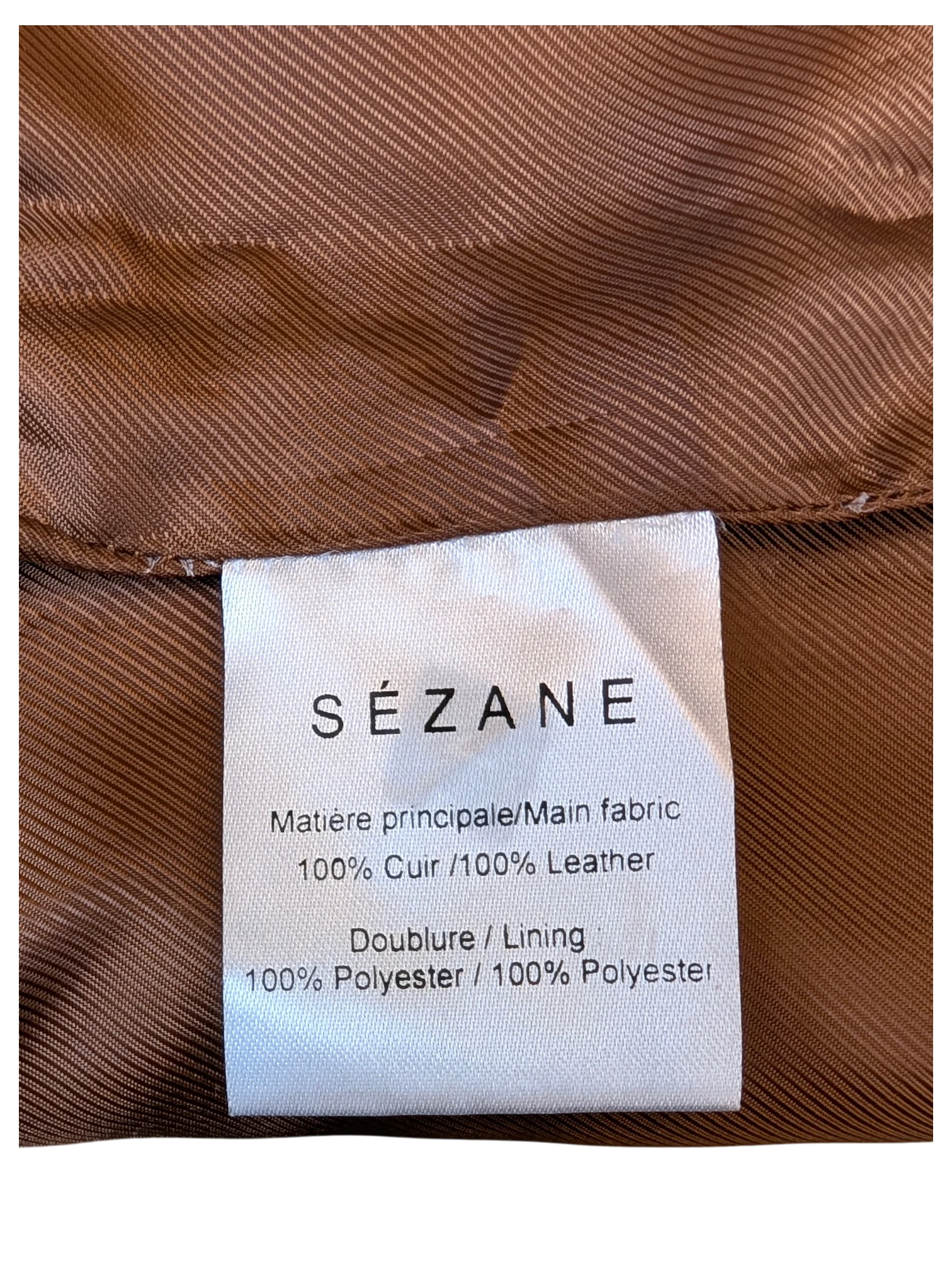 JAKE & IPI Sézane leather skirt care label showing 100% leather and 100% polyester lining on brown fabric.