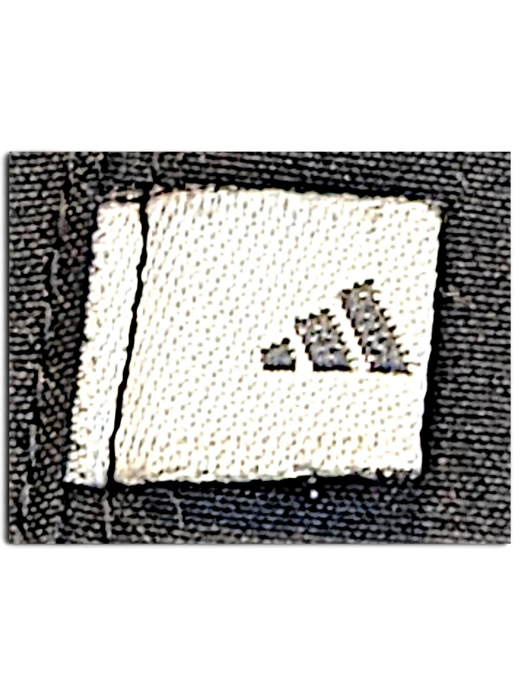 JAKE & IPI adidas dark grey track pants featuring a close-up of the embroidered logo patch on the fabric