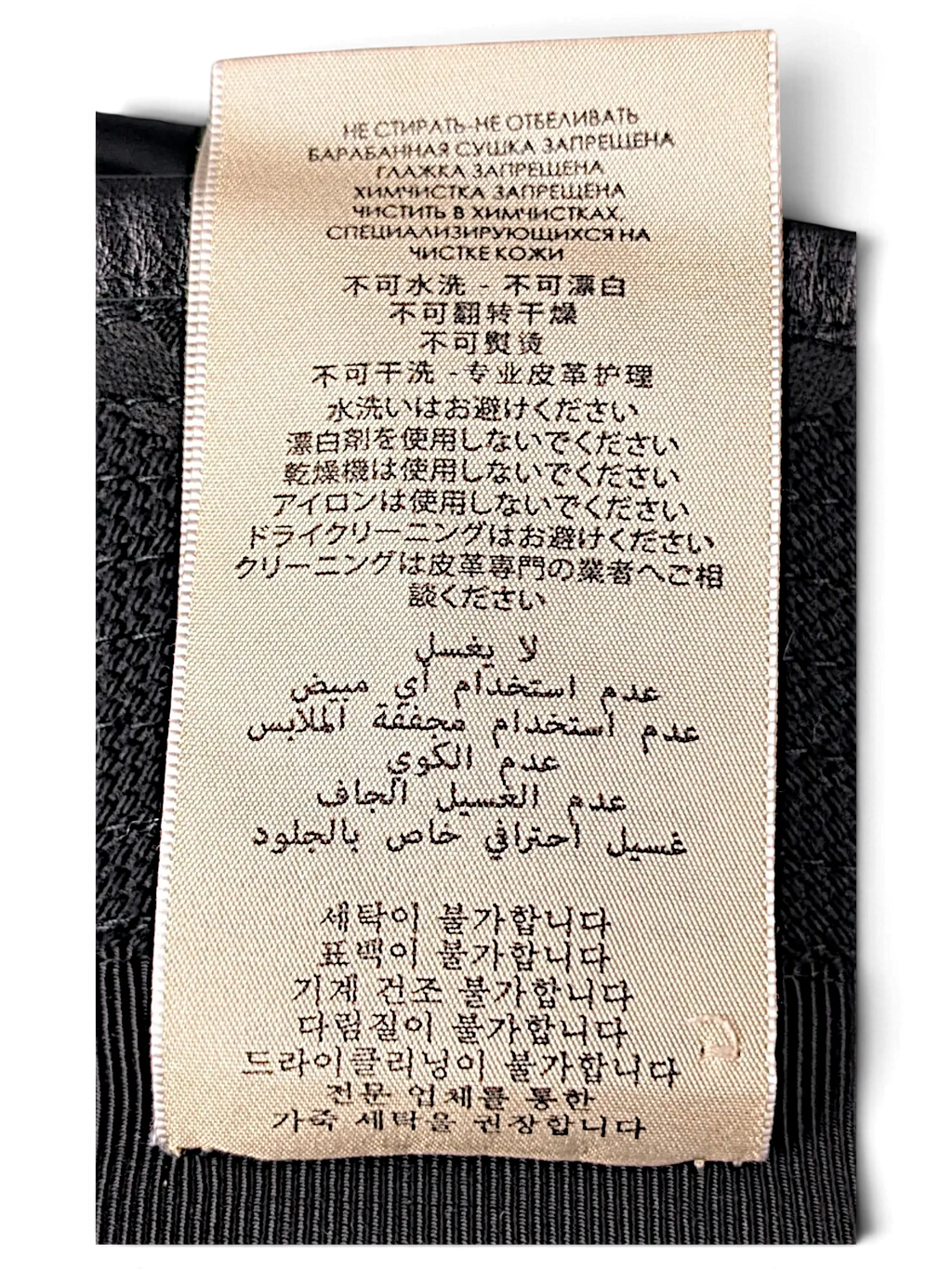 JAKE & IPI bucket hat care label with multi-language washing instructions printed on a beige fabric tag