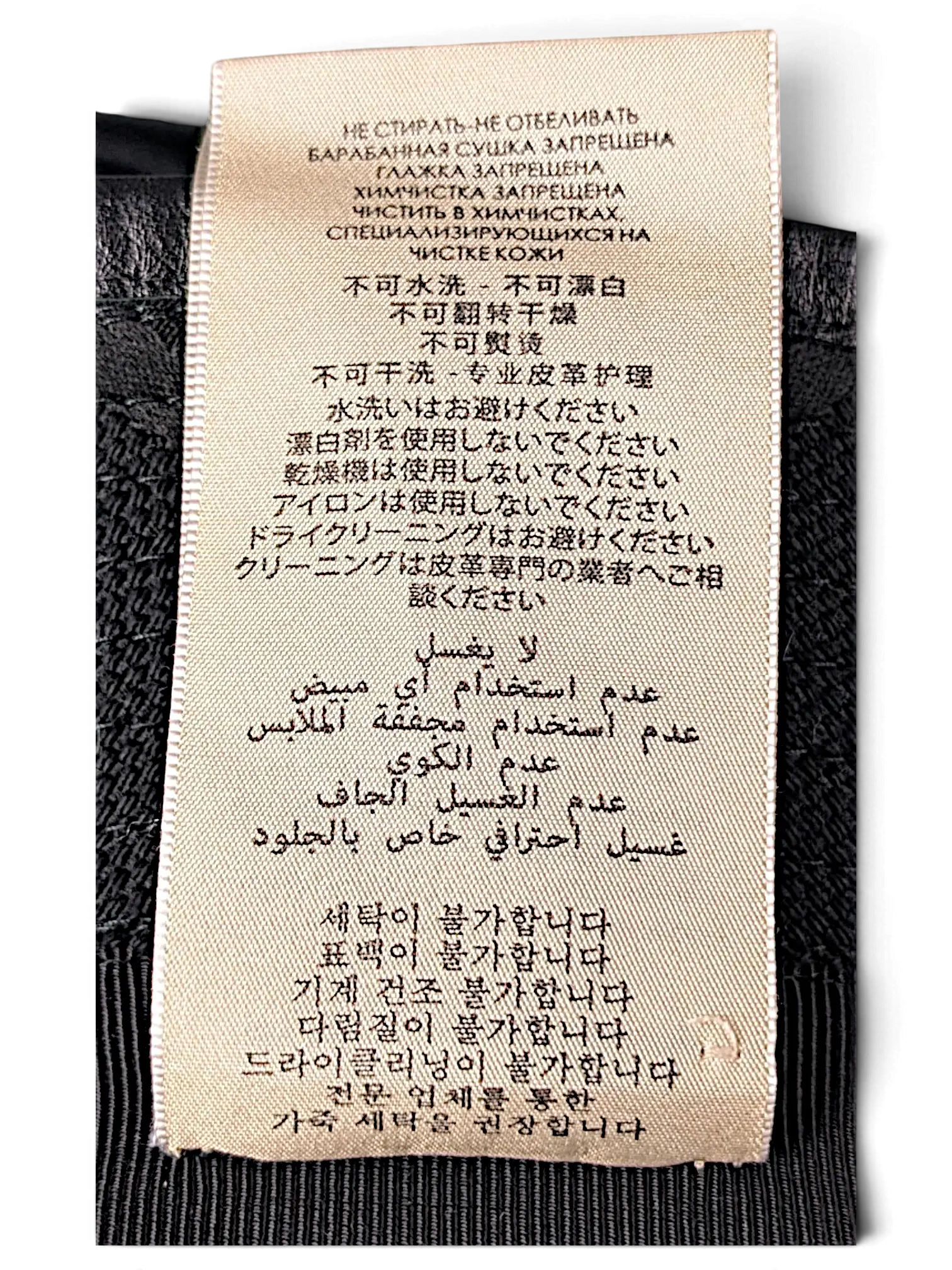 JAKE & IPI bucket hat care label with multi-language washing instructions printed on a beige fabric tag