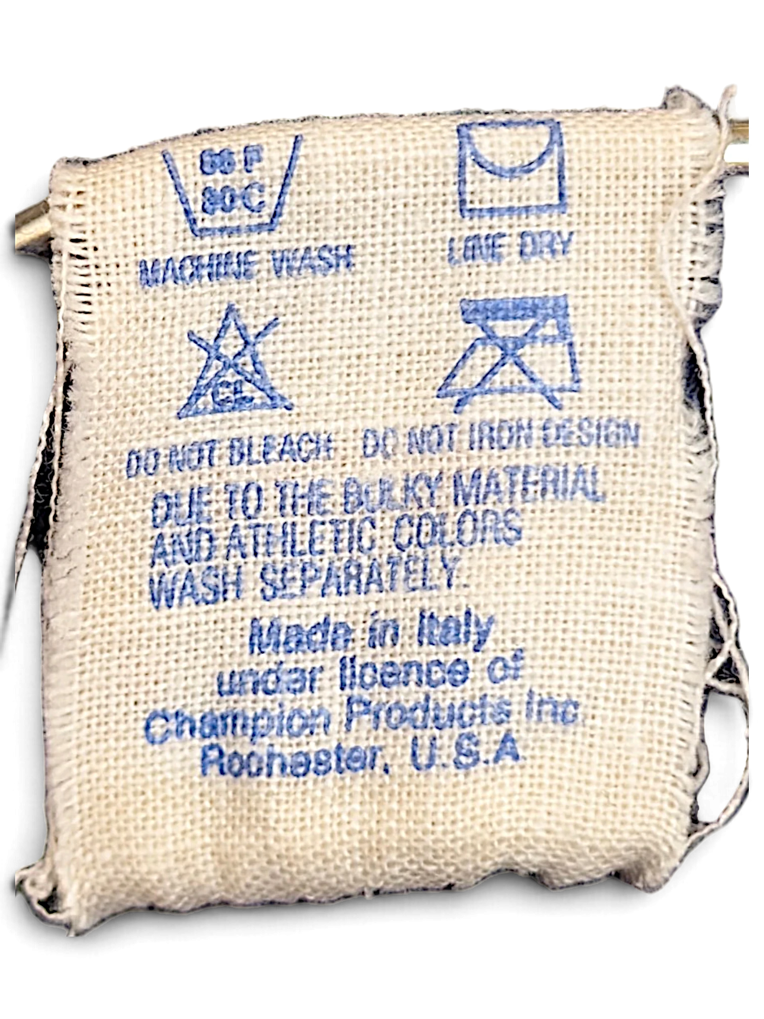 JAKE & IPI Champion track pants care label with washing instructions and origin details on a woven fabric tag