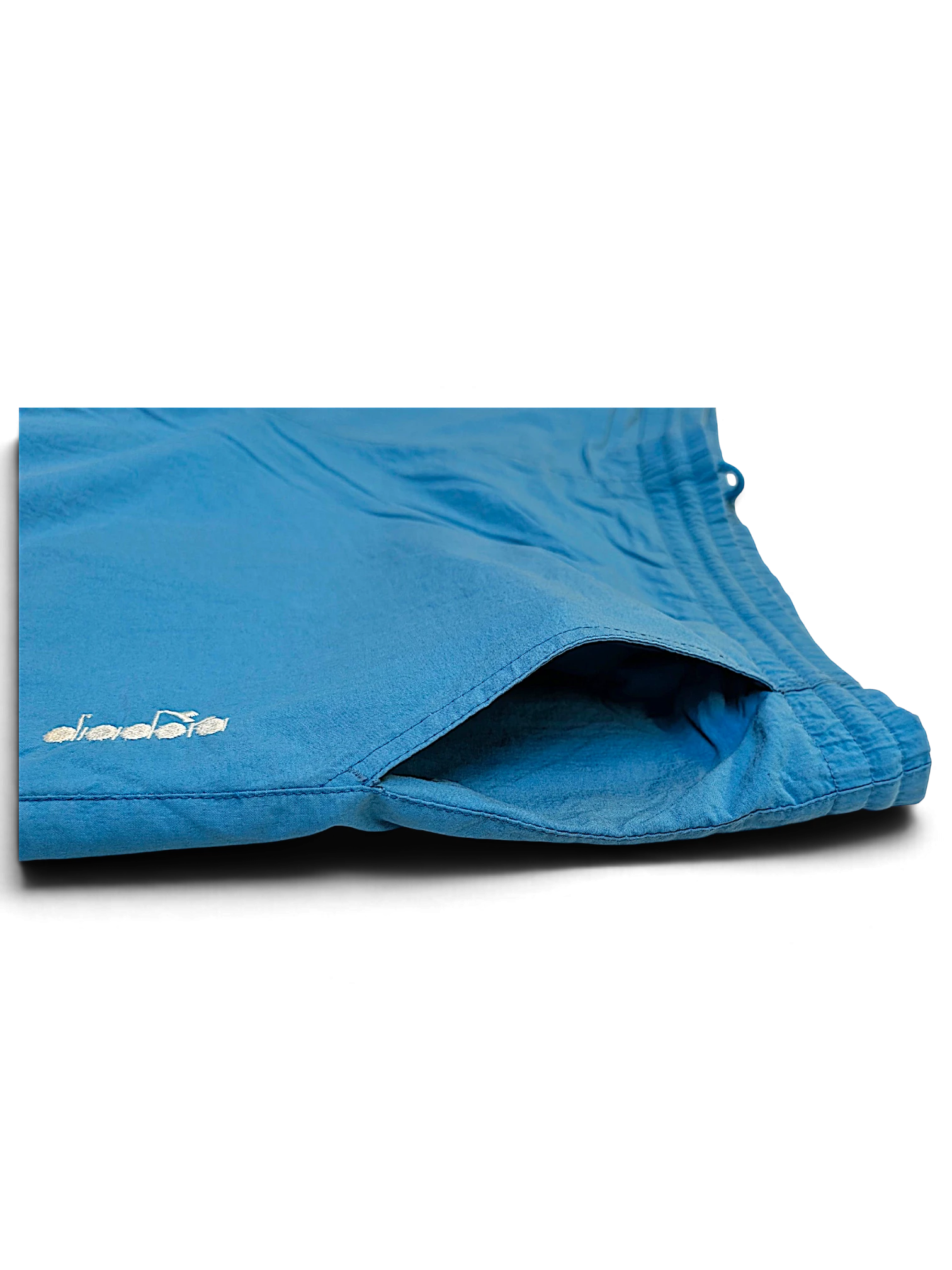 JAKE & IPI pre-owned Diadora track pants in faded light blue with an embroidered logo and side pocket detail.