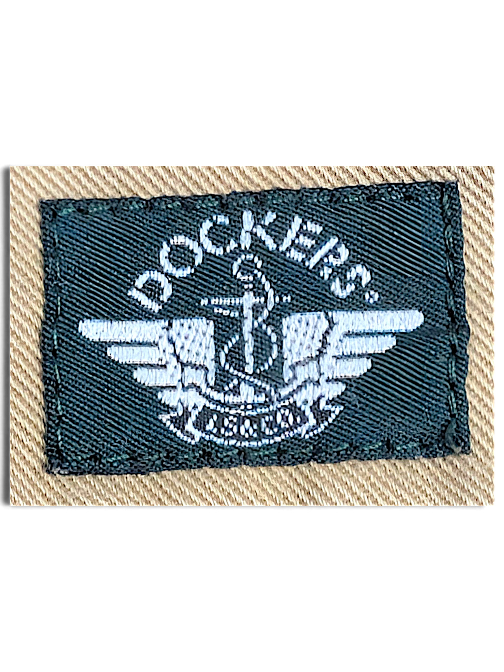 JAKE & IPI Dockers brand logo label embroidered in white on a dark green patch against beige cotton fabric