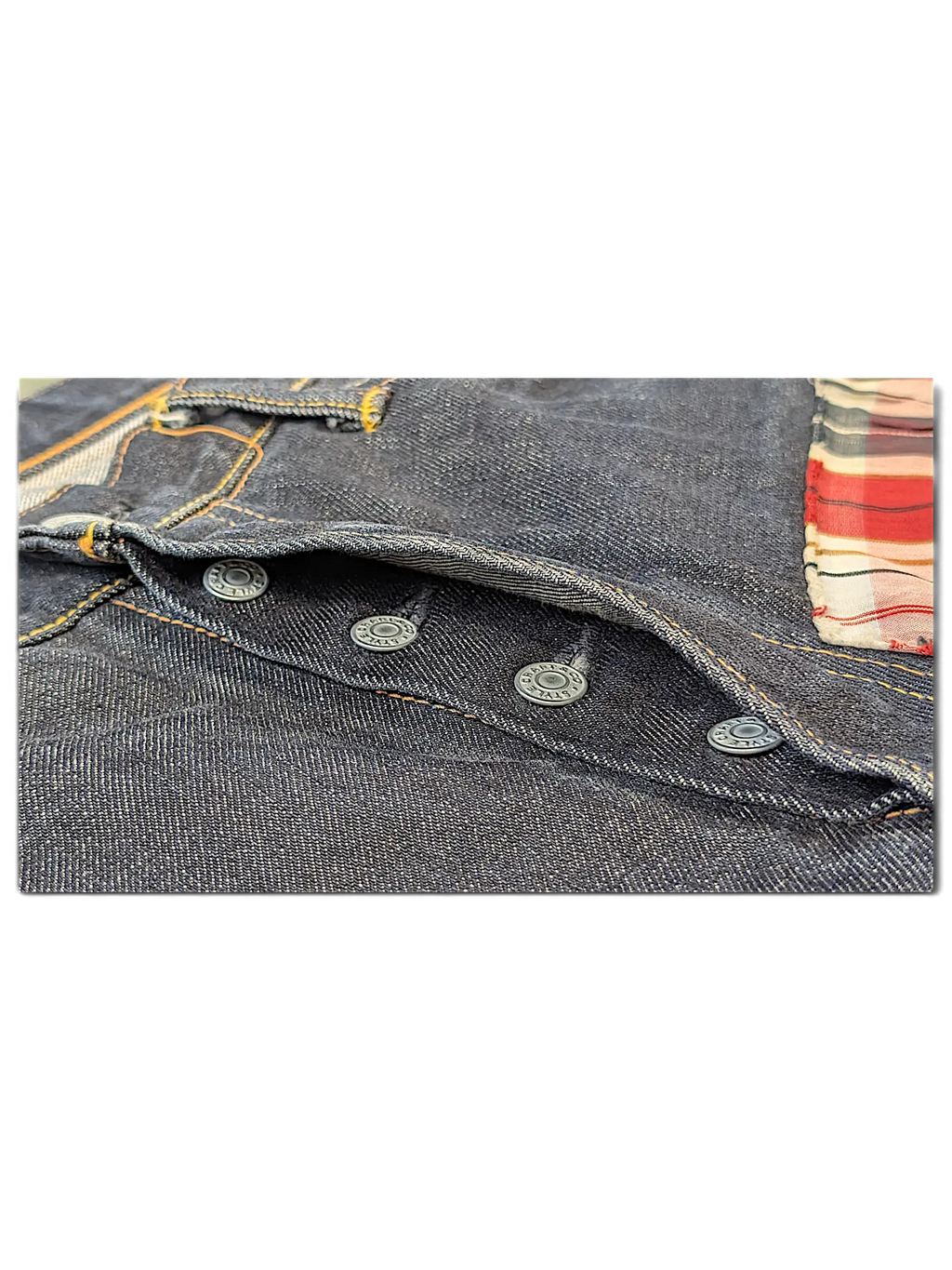 JAKE & IPI Evisu One Of One dark denim jeans featuring a button fly and red plaid interior pocket lining detail.