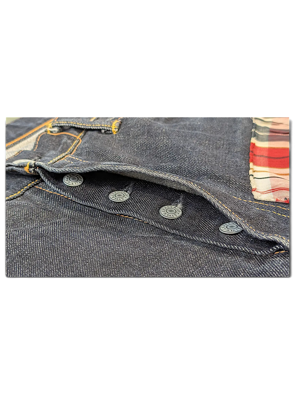 JAKE & IPI Evisu One Of One dark denim jeans featuring a button fly and red plaid interior pocket lining detail.