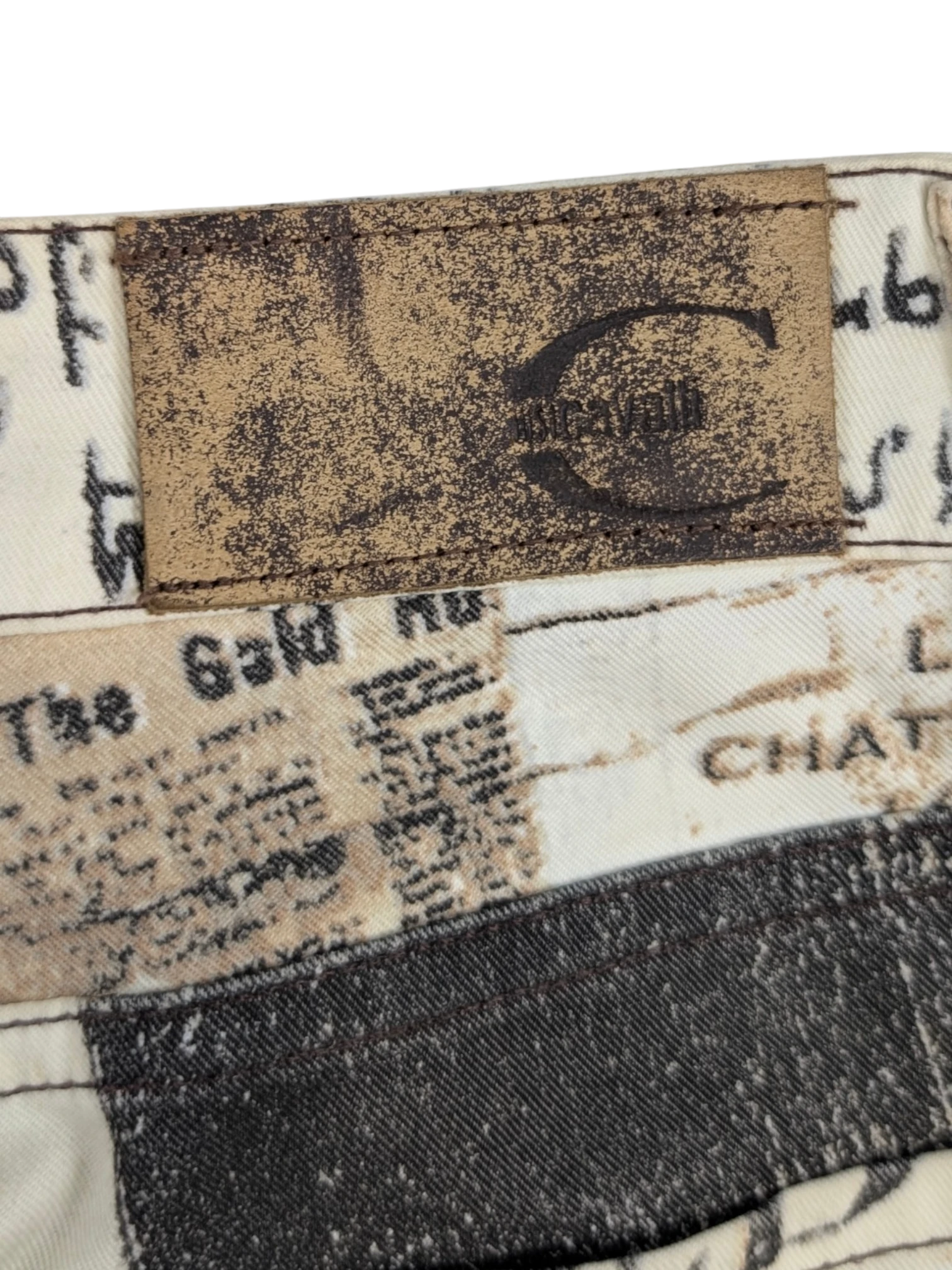 JAKE & IPI Just Cavalli newspaper print jeans in sepia, cream, and black. Slim fit, mid-rise waist, 5-pocket design. Y2K era.