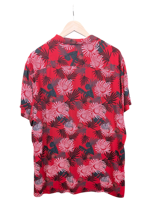 JAKE & IPI Angelo Litrico red Hawaiian shirt featuring a tropical floral and palm leaf print on a hanger