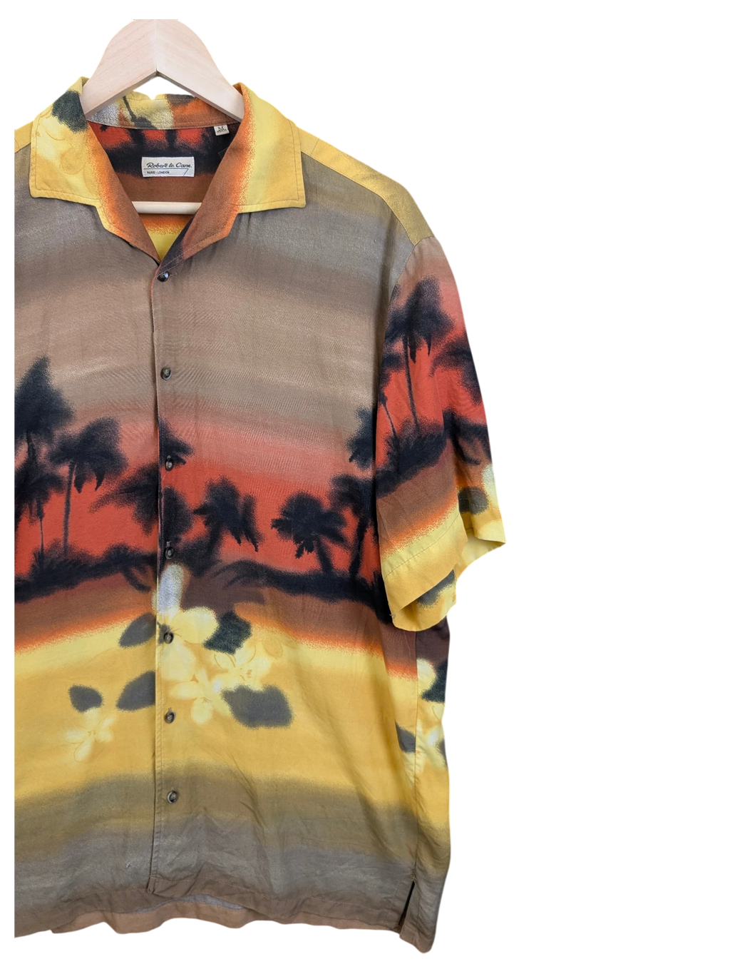 JAKE & IPI Robert Le Cam Hawaiian shirt featuring a sunset palm tree landscape print in warm yellow and orange tones.