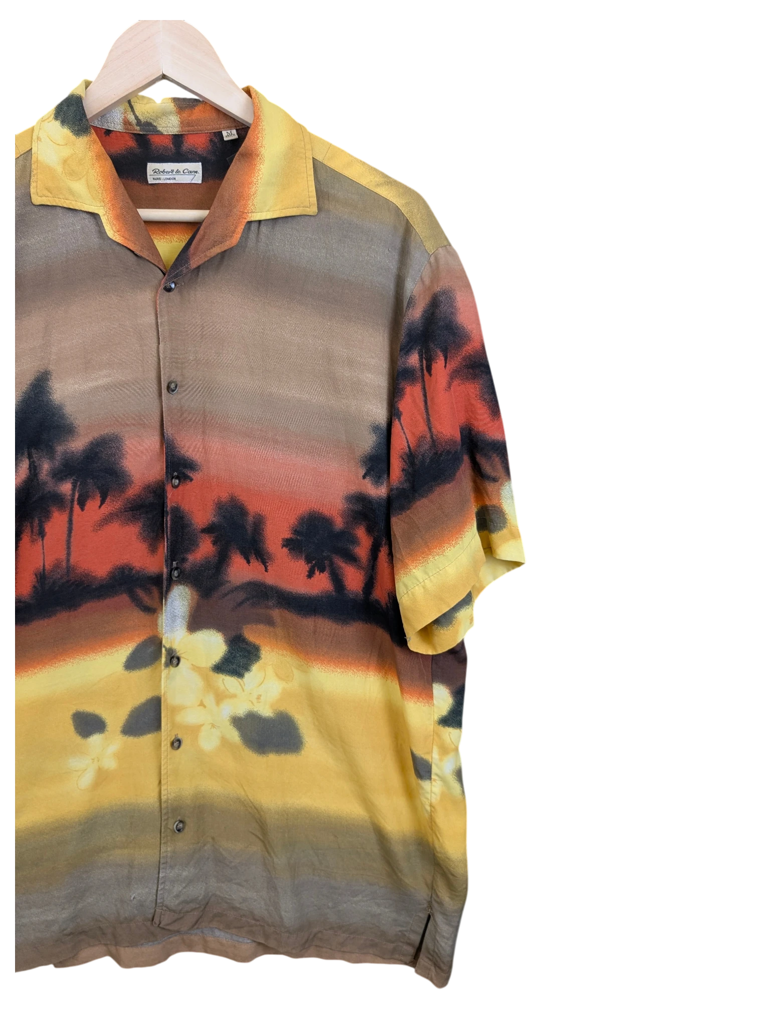 JAKE & IPI Robert Le Cam Hawaiian shirt featuring a sunset palm tree landscape print in warm yellow and orange tones.