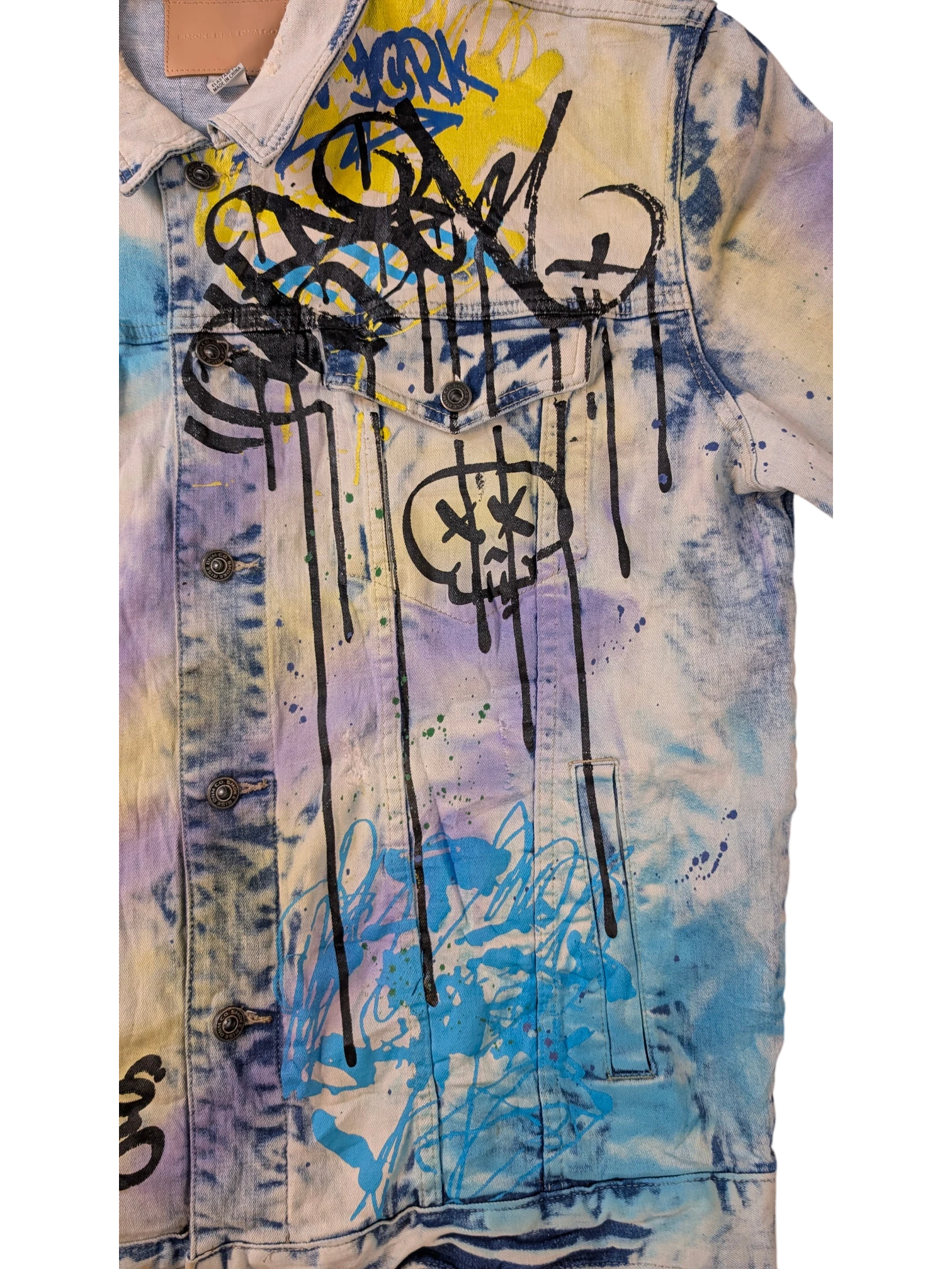 JAKE & IPI Smoke Rise denim jacket with graffiti-style paint splatters in yellow, blue, purple, and black.