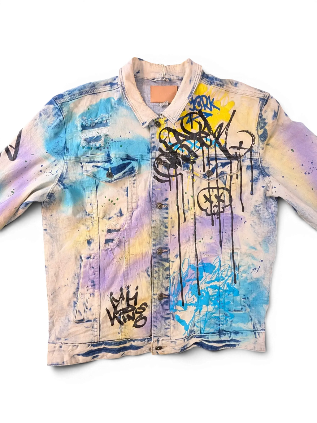 JAKE & IPI Smoke Rise denim jacket with graffiti print, distressed details, and tie-dye effect in blue, yellow, and purple.
