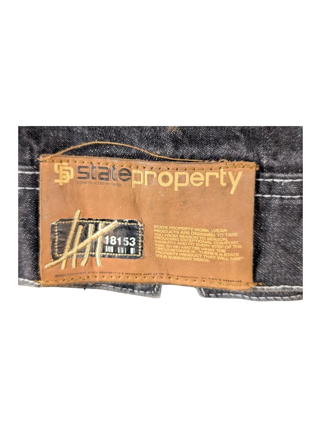 JAKE & IPI State Property dark wash denim jacket with brown leather logo patch and white stitching.