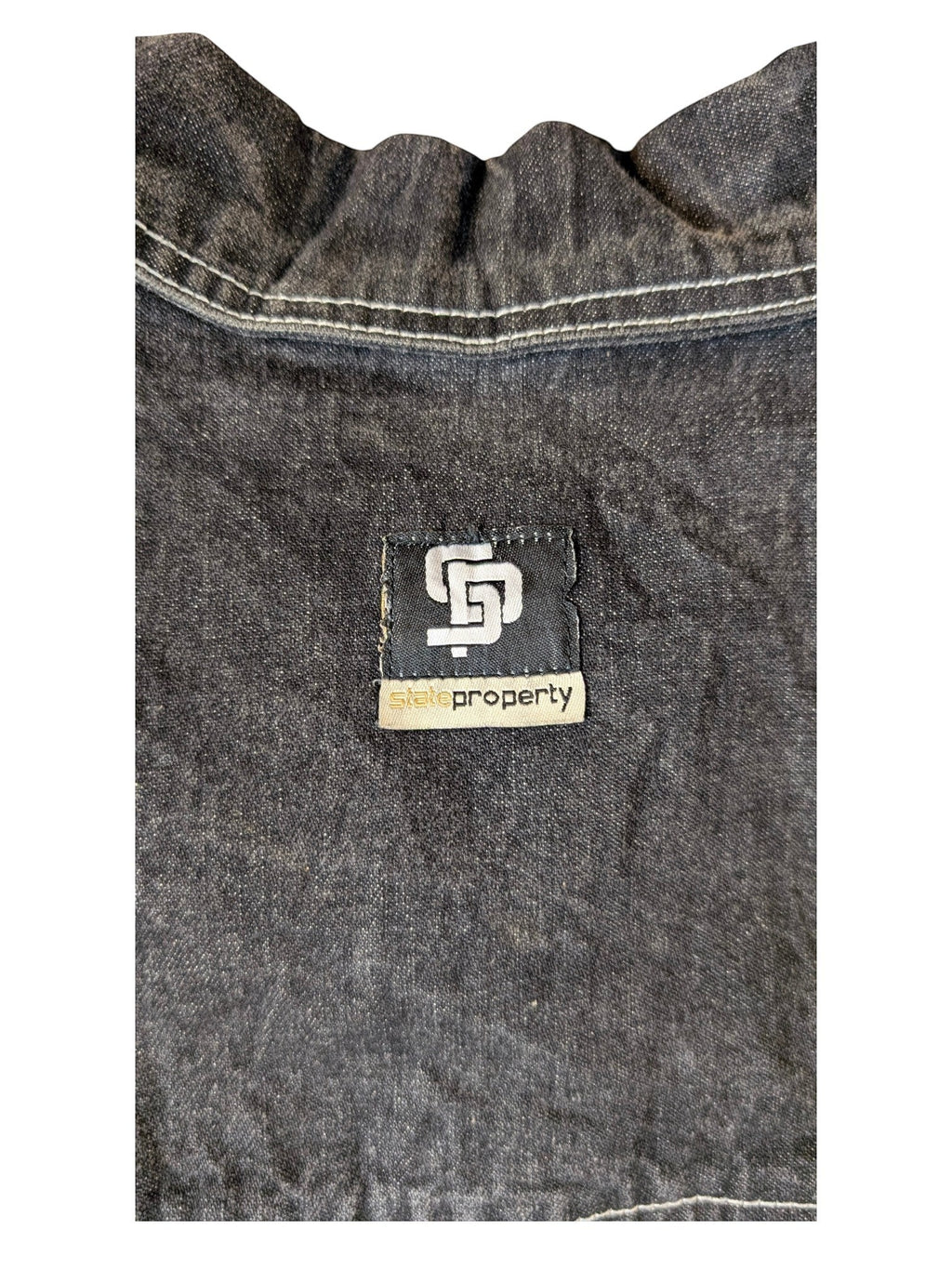 JAKE & IPI State Property dark wash denim jacket with white contrast stitching and a black logo patch.