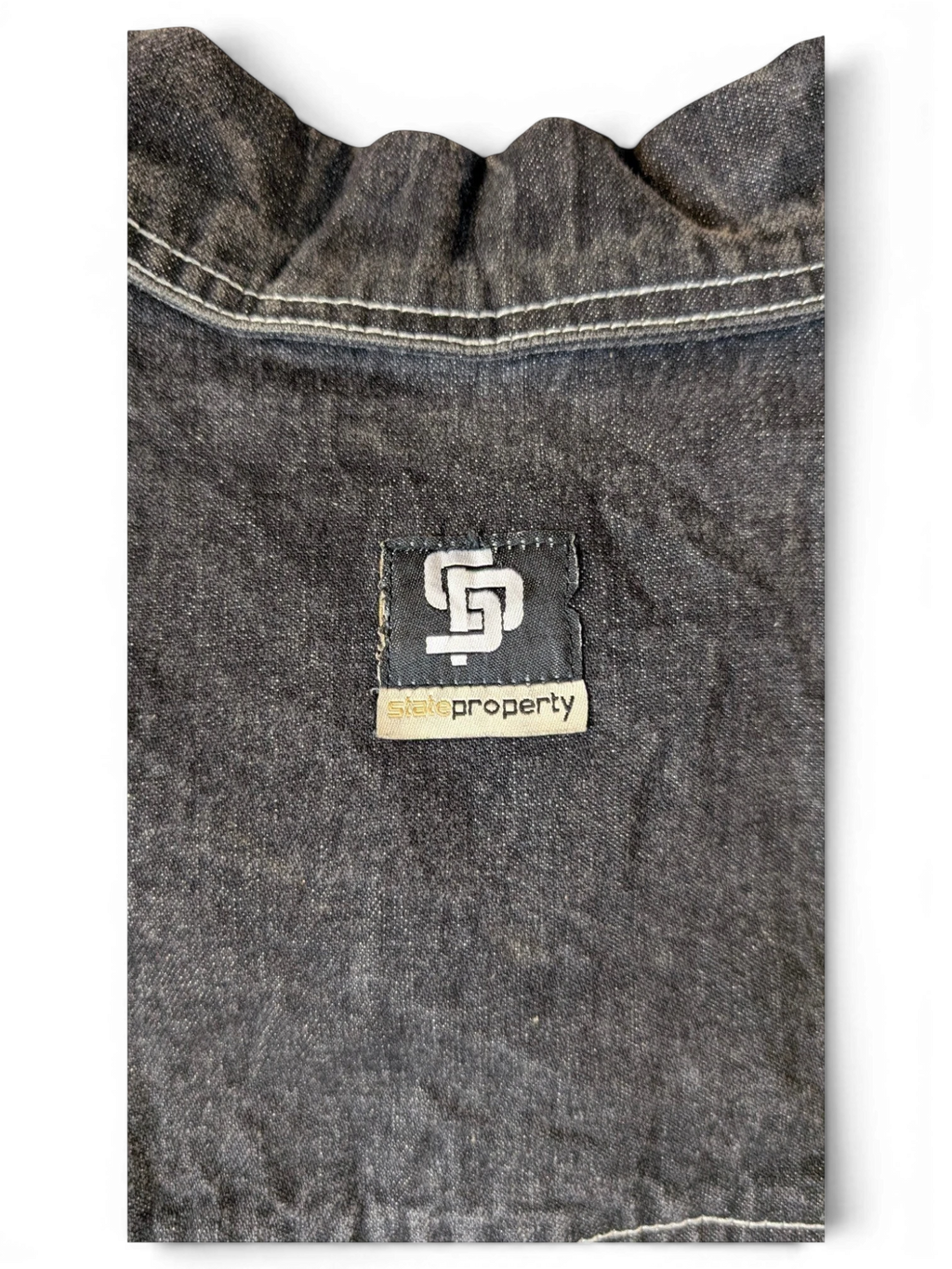 JAKE & IPI State Property dark wash denim jacket with white contrast stitching and a black logo patch.