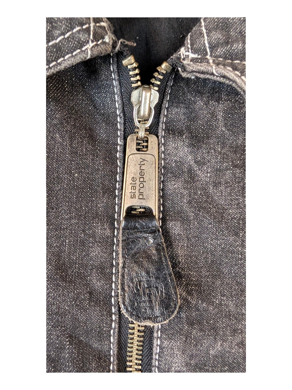 JAKE & IPI State Property dark wash denim jacket with silver zipper and white stitching.