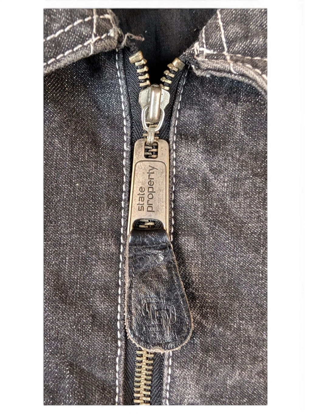 JAKE & IPI State Property dark wash denim jacket with silver zipper and white stitching.