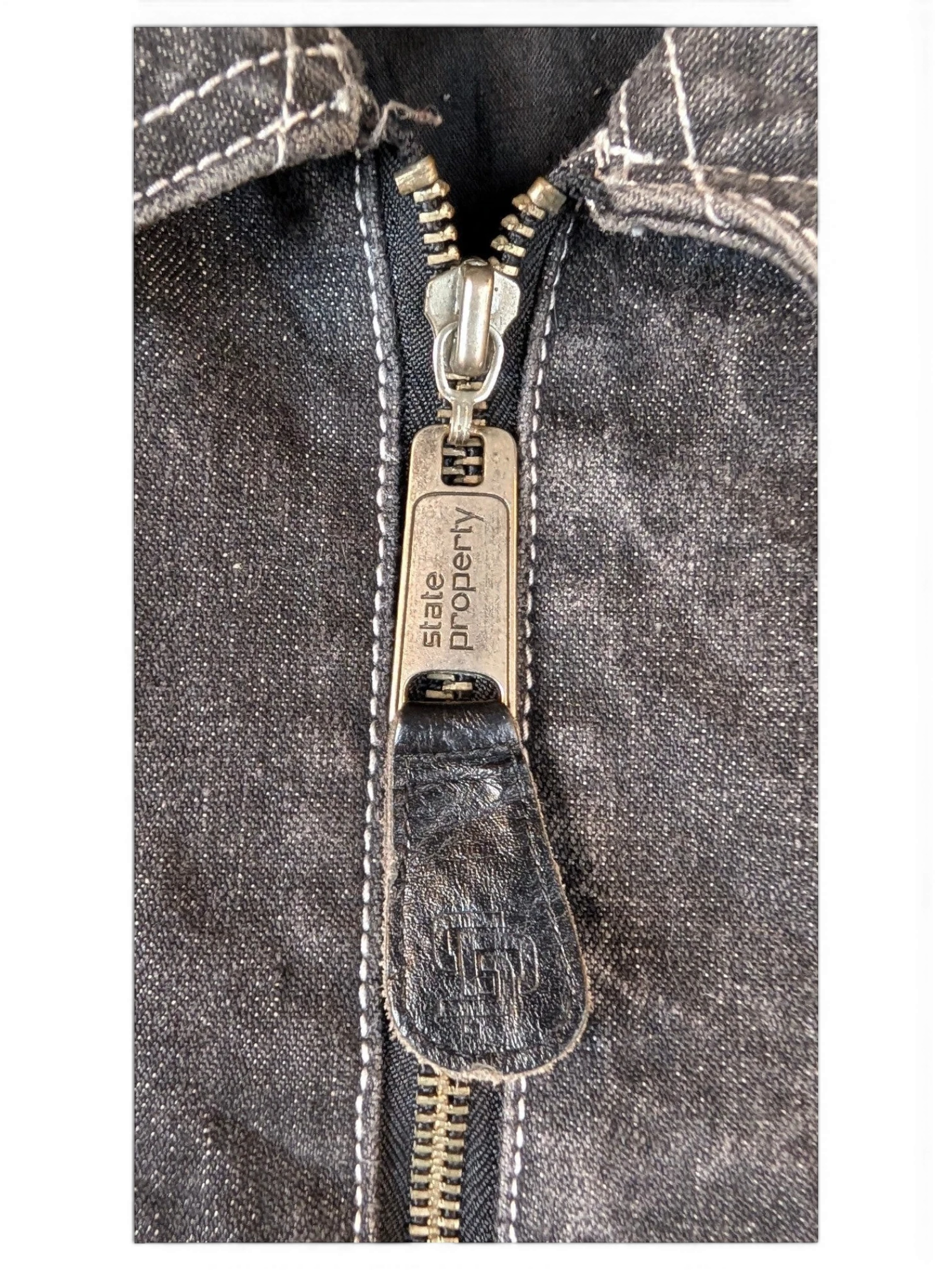 JAKE & IPI State Property dark wash denim jacket with silver zipper and white stitching.