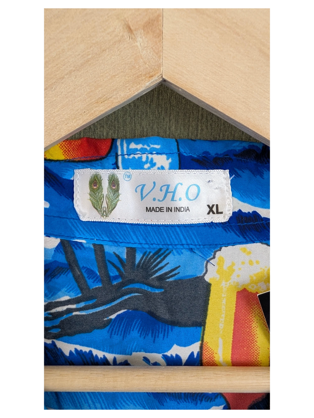 JAKE & IPI V.H.O Hawaiian shirt featuring a vibrant blue tropical print on a wooden hanger