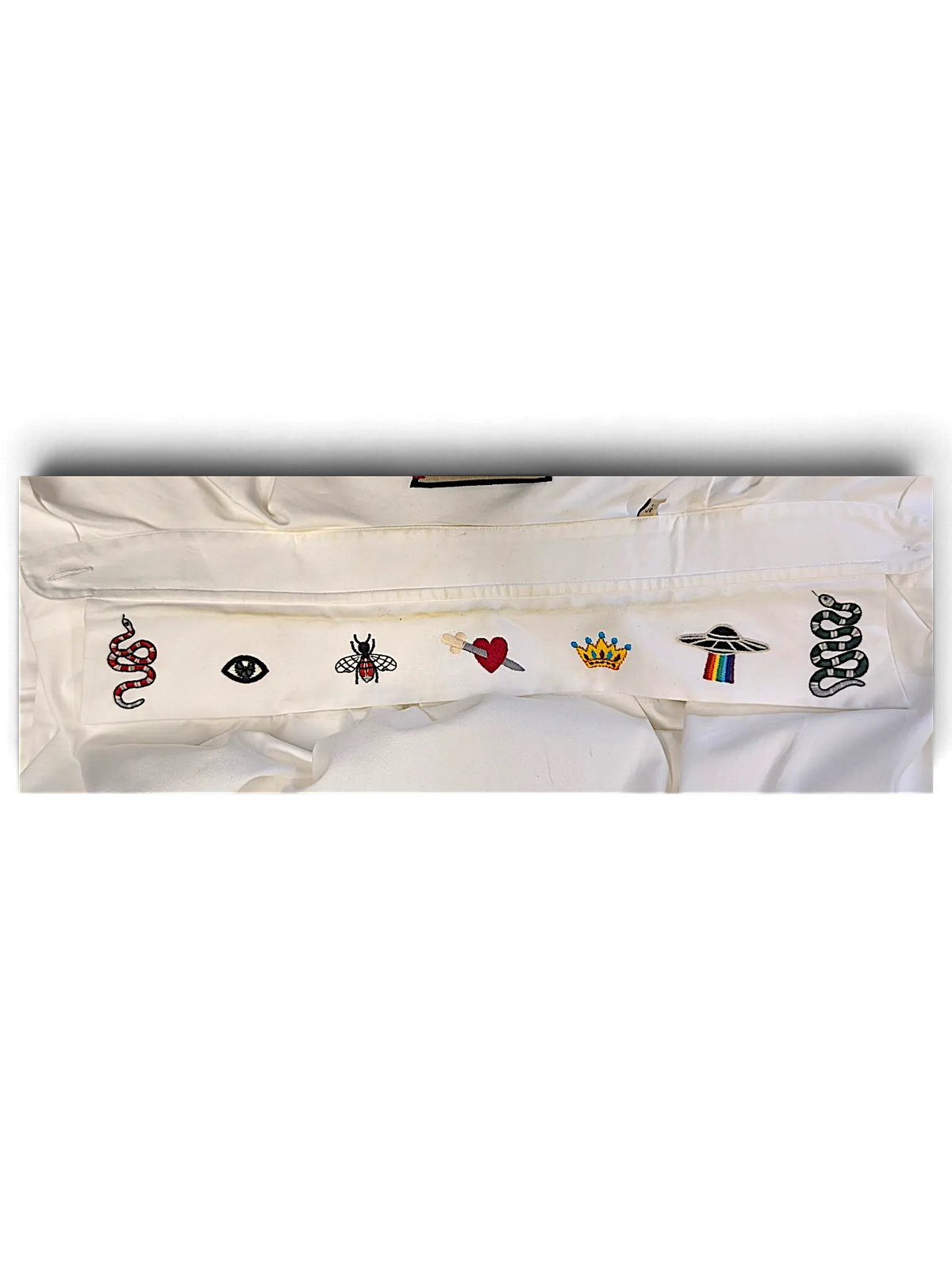 JAKE & IPI white IBE Gucci shirt featuring embroidered patches of a snake, eye, bee, heart, crown, and UFO.