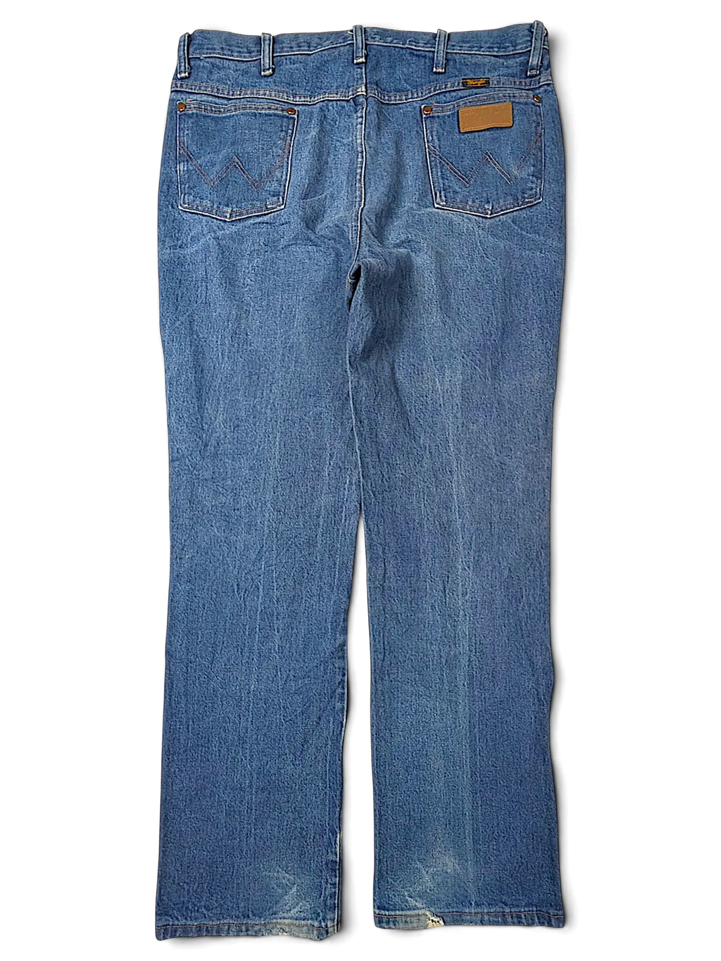 JAKE & IPI Wrangler 936DEN blue denim jeans featuring back pockets with signature stitching and a leather patch.
