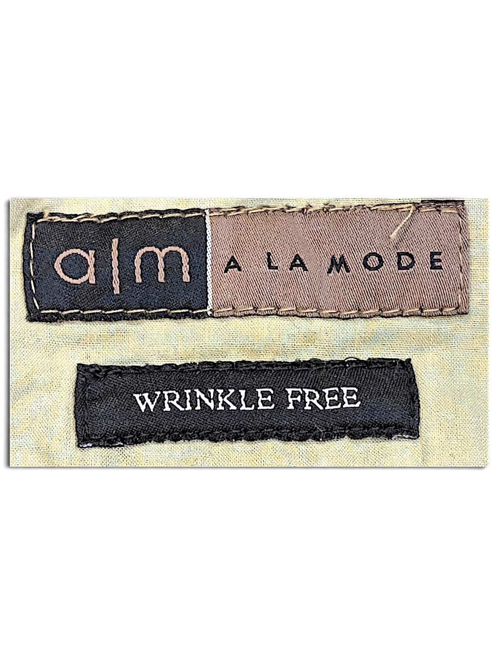 JAKE & IPI A M A La Mode clothing label featuring the brand name and a Wrinkle Free tag on a beige fabric background.