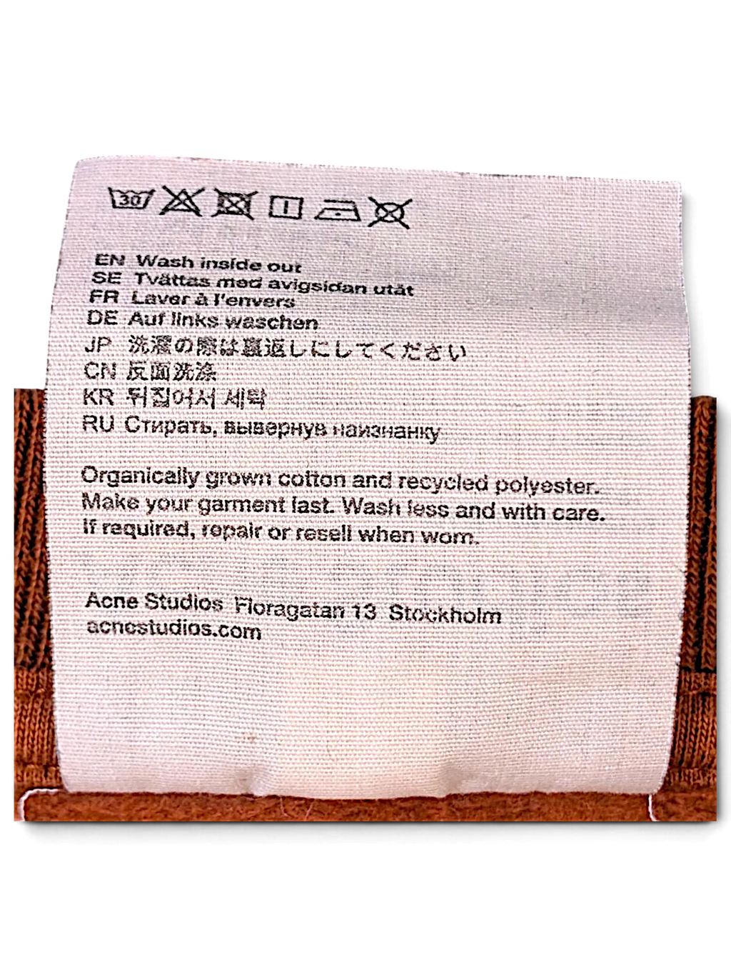 JAKE & IPI brown IBE Acne garment care label with washing instructions on organic cotton and recycled polyester fabric
