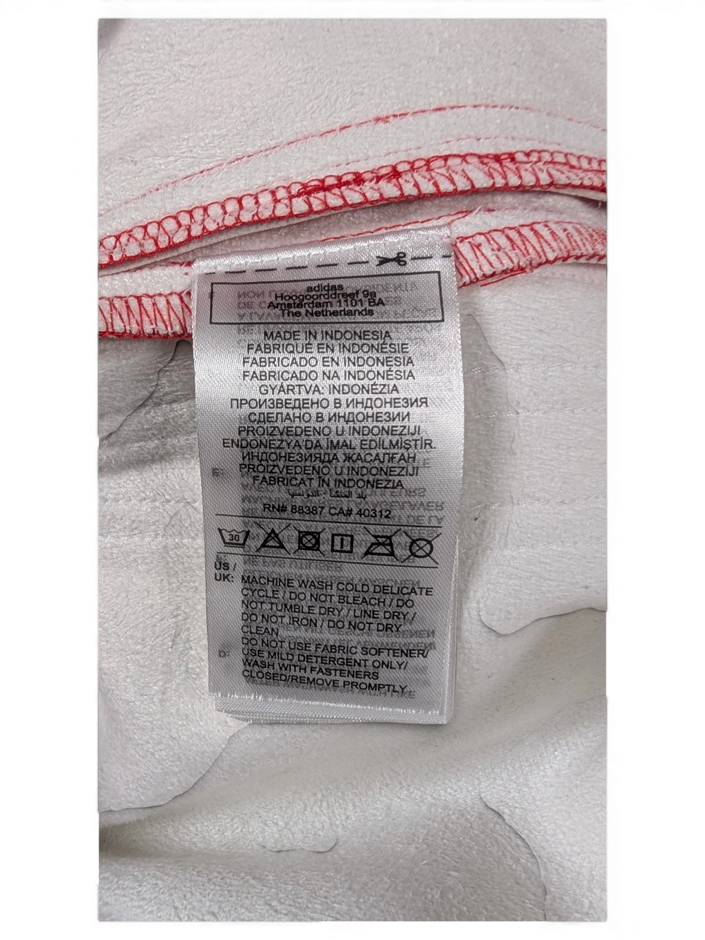 JAKE & IPI Adidas red and white garment care label with washing instructions and manufacturing details