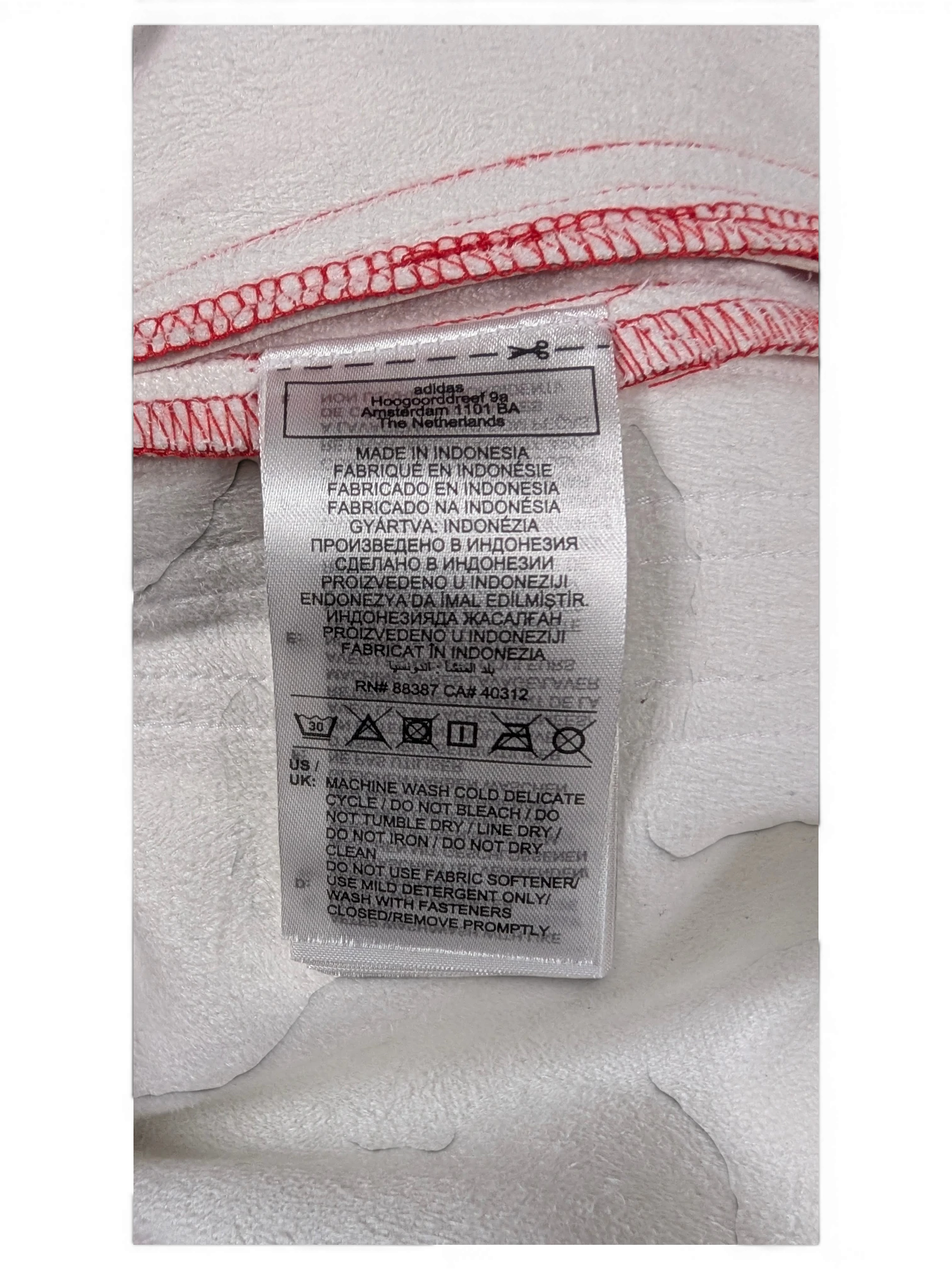 JAKE & IPI Adidas red and white garment care label with washing instructions and manufacturing details