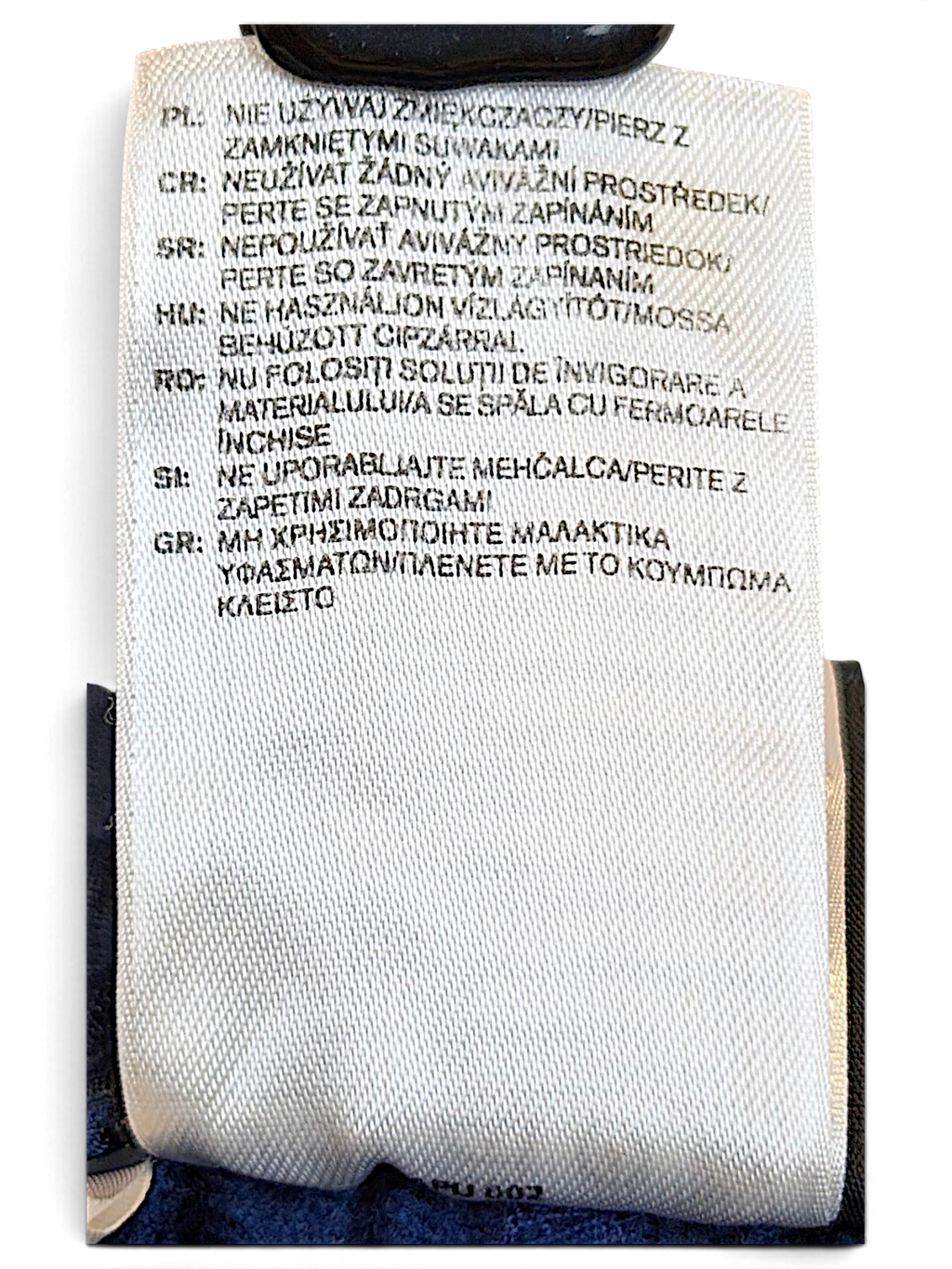 JAKE & IPI adidas track pants care label with multi-language washing instructions on white fabric