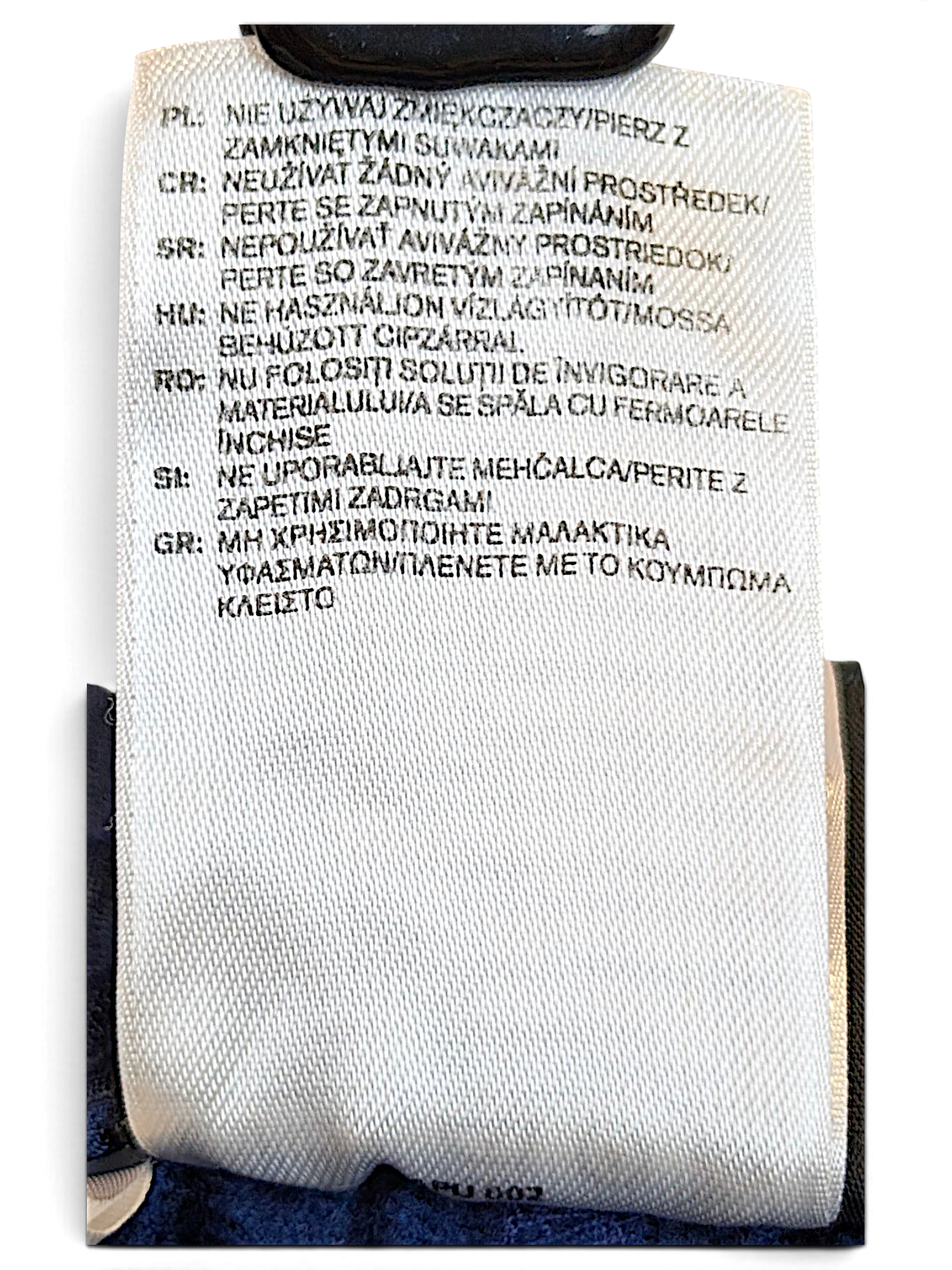 JAKE & IPI adidas track pants care label with multi-language washing instructions on white fabric