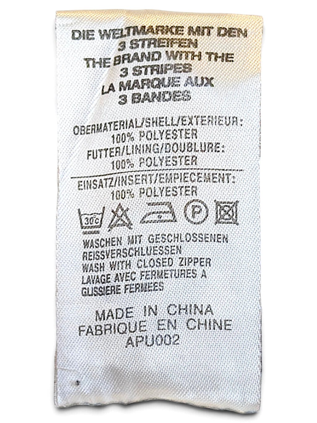 JAKE & IPI adidas track pants care label showing 100 percent polyester composition and washing instructions