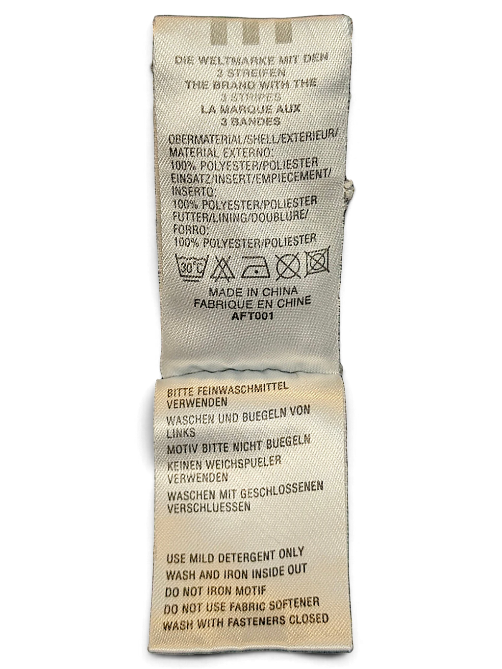 JAKE & IPI adidas track pants care and material label showing 100 percent polyester composition and washing instructions