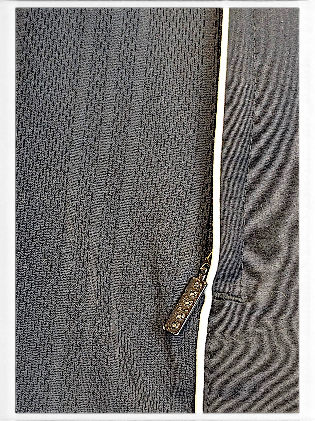 Close-up of JAKE & IPI adidas grey track pants featuring textured fabric and a metallic zipper pull detail.