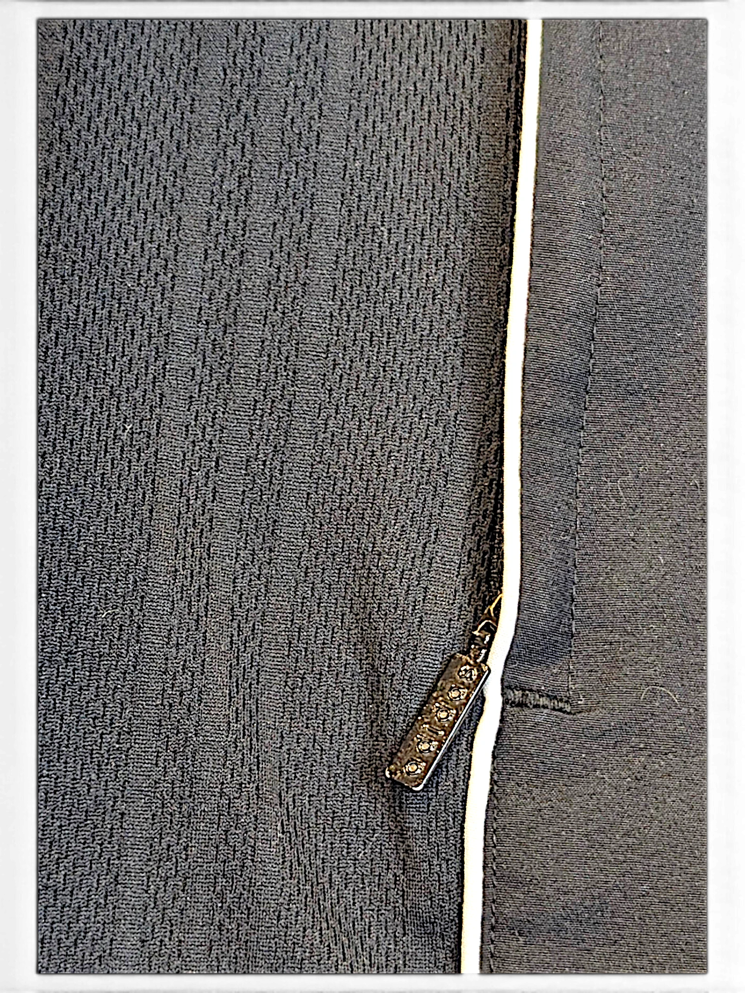 Close-up of JAKE & IPI adidas grey track pants featuring textured fabric and a metallic zipper pull detail.